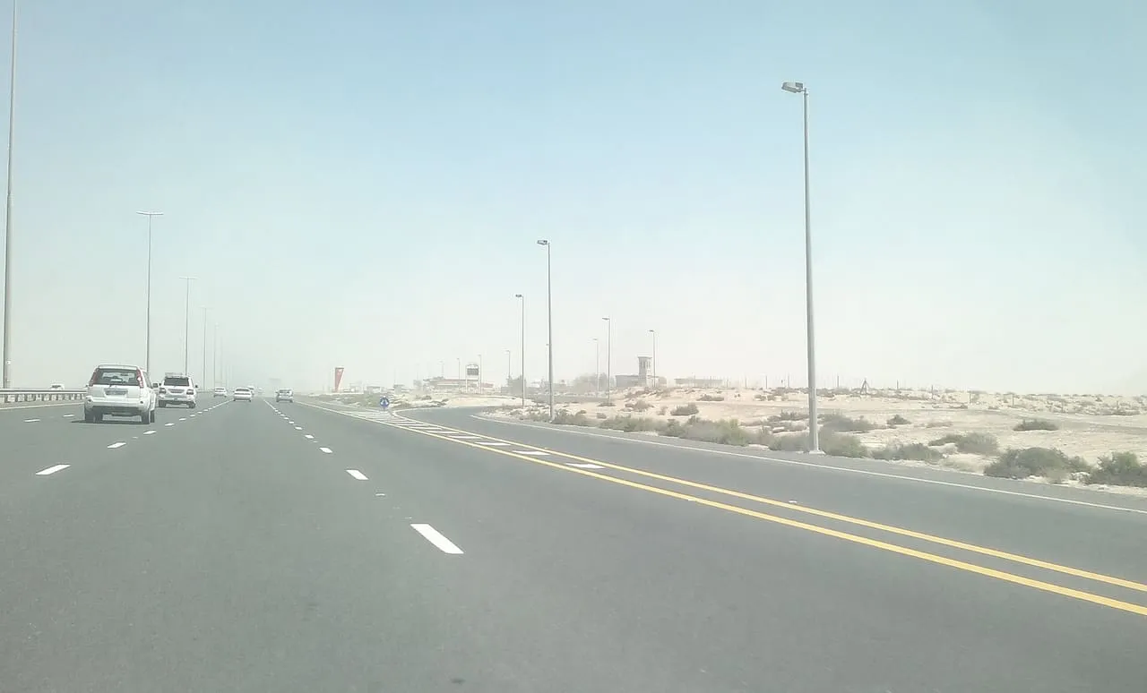 A wide, quiet stretch of the motorway between Abu Dhabi and Dubai, with desert along the roadside