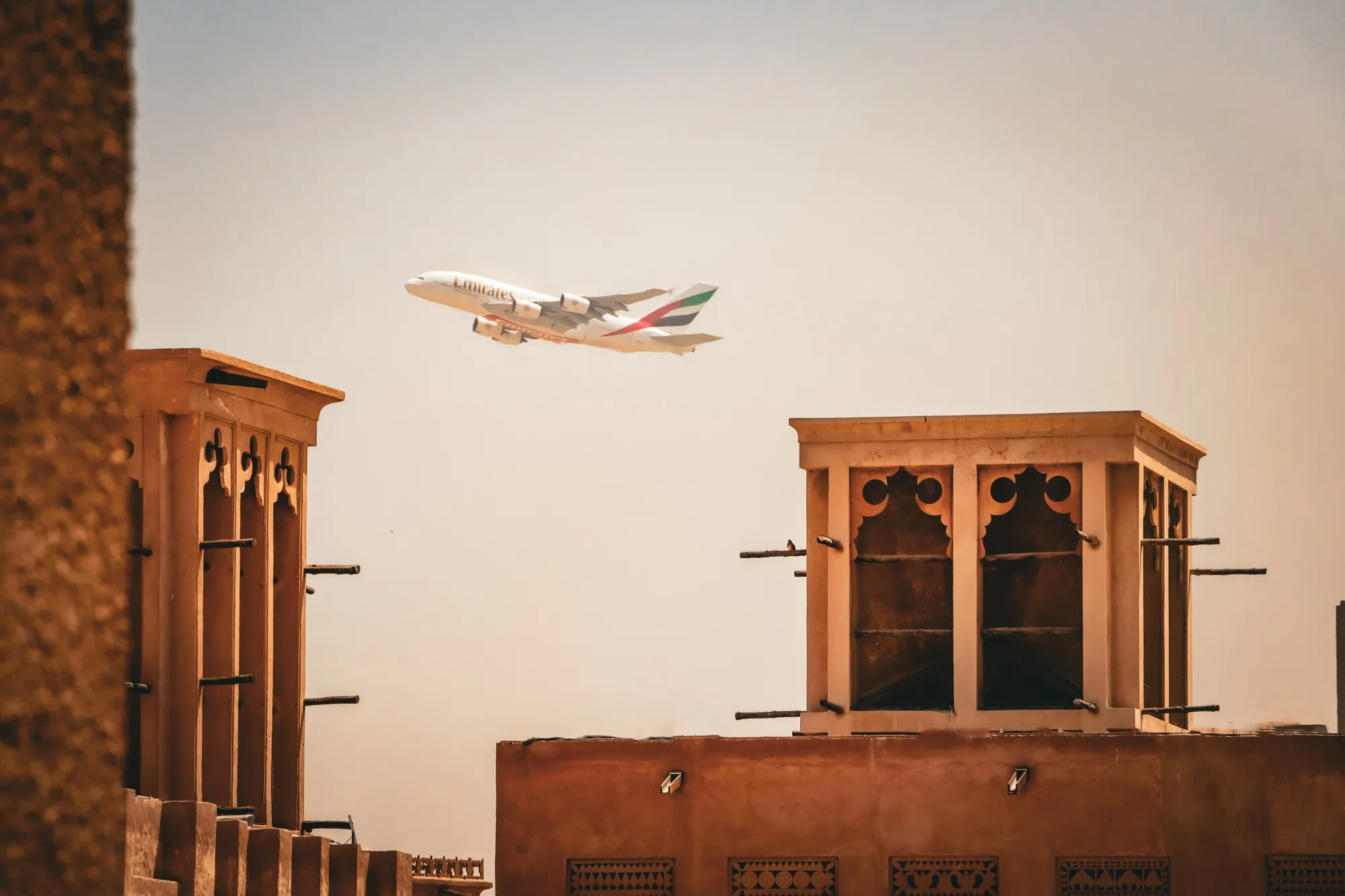 Wind towers in Al Fahidi Historical Neighbourhood, with an Emirates A380 passing overhead