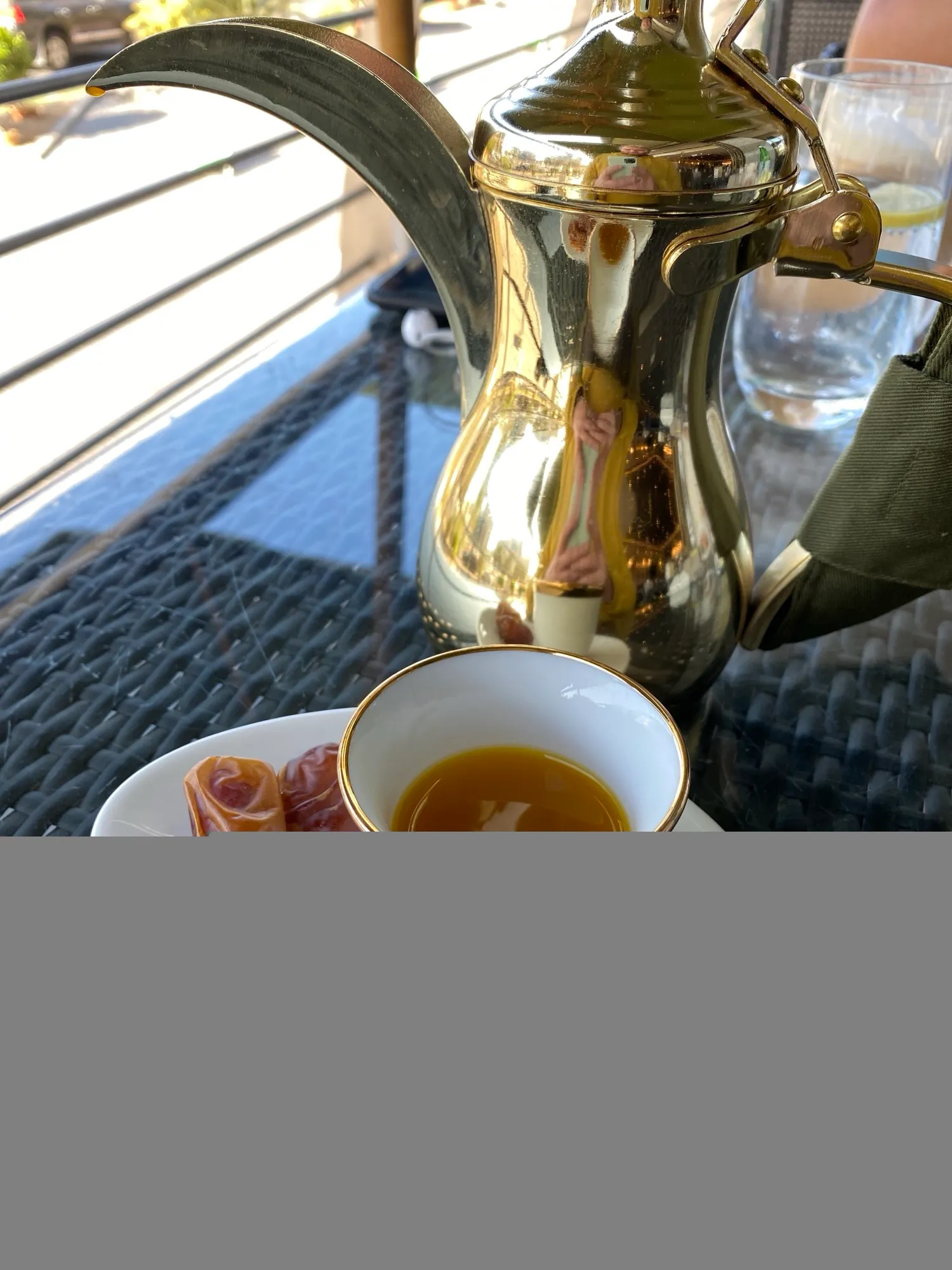 An Arabic coffee dallah, a cup of coffee and dates on a table