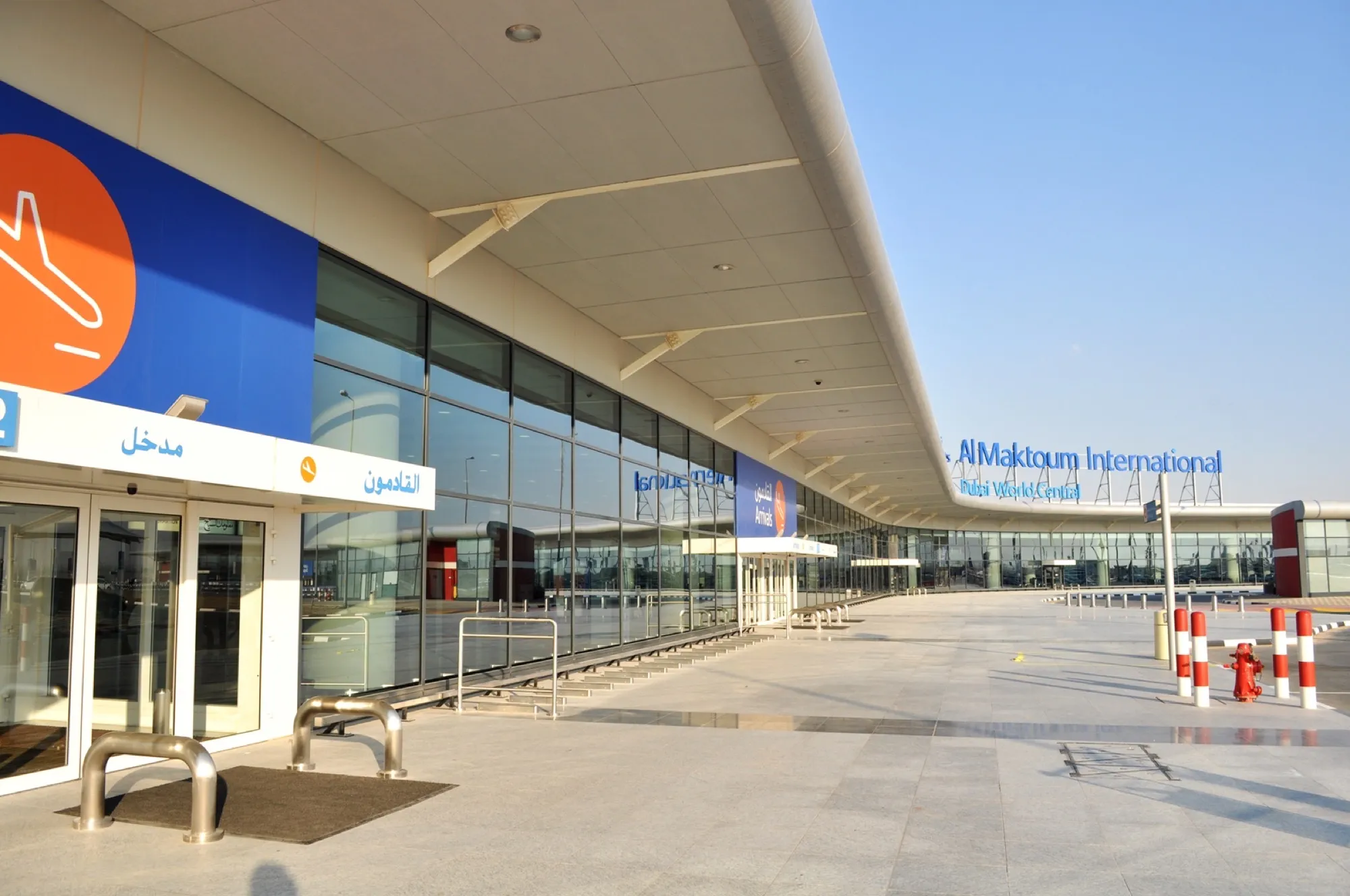 The arrivals entrance and curved canopy of the passenger terminal at Al Maktoum International Airport, Dubai World Central