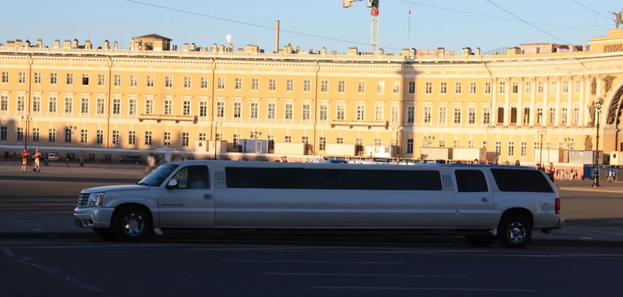 Side view of a white Cadillac Escalade stretch limousine, a representative image, not the partner's car