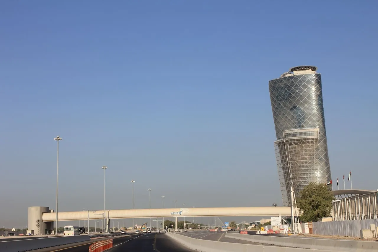 The leaning Capital Gate tower at ADNEC Centre Abu Dhabi, seen from the road with a pedestrian bridge in front