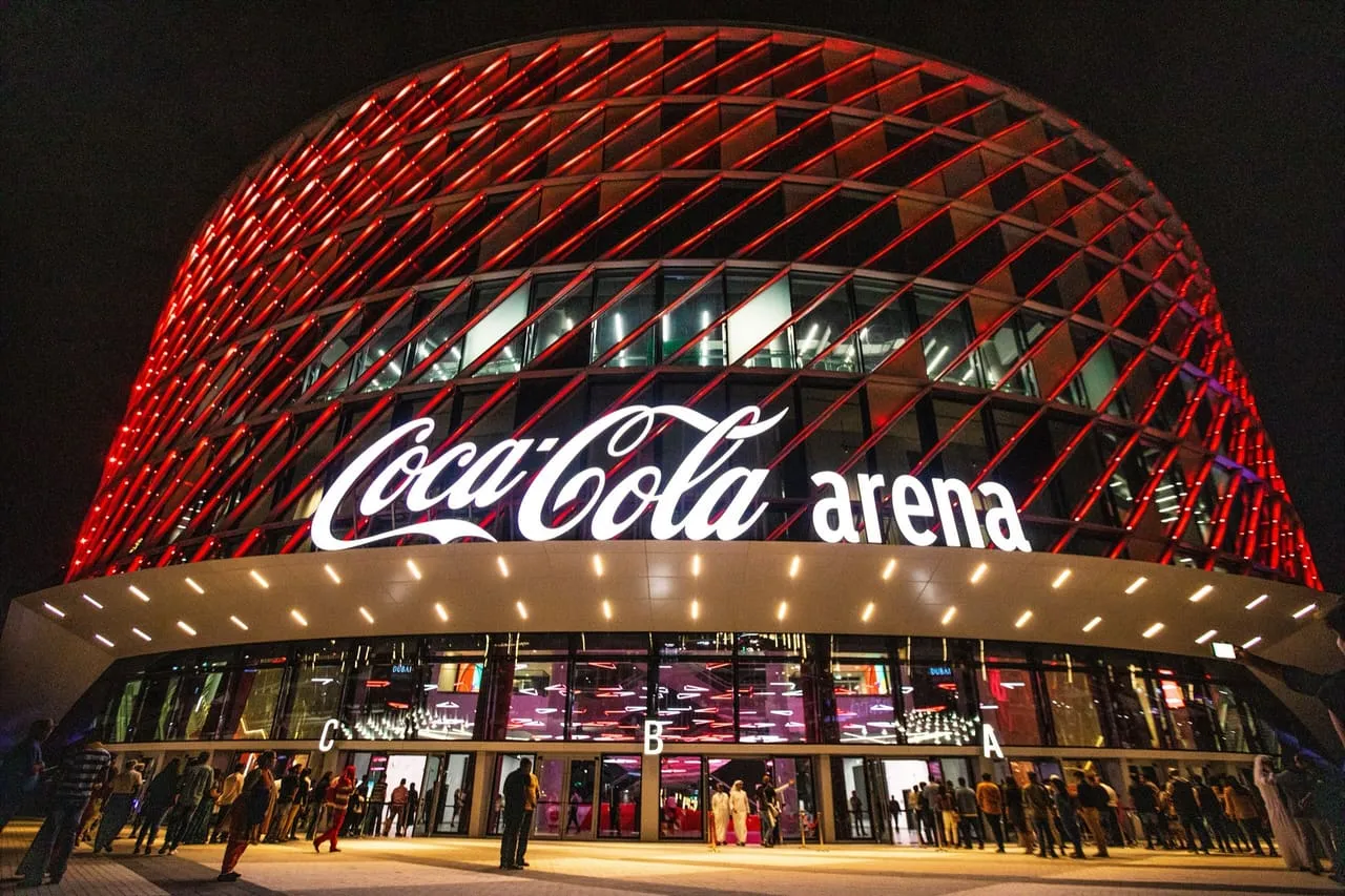 The front of Coca-Cola Arena in City Walk at night, with entrances C, B and A under the lit canopy