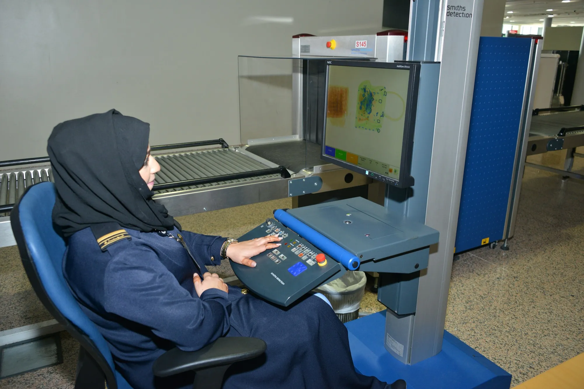 A customs officer watching an X-ray baggage scanner screen at Dubai airport