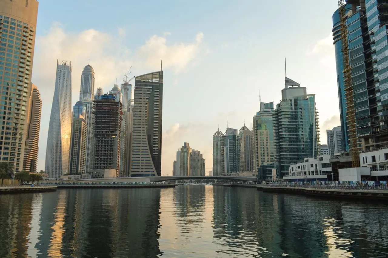 The Dubai Marina canal at dusk, with the Cayan Tower and other high-rises reflected in the water