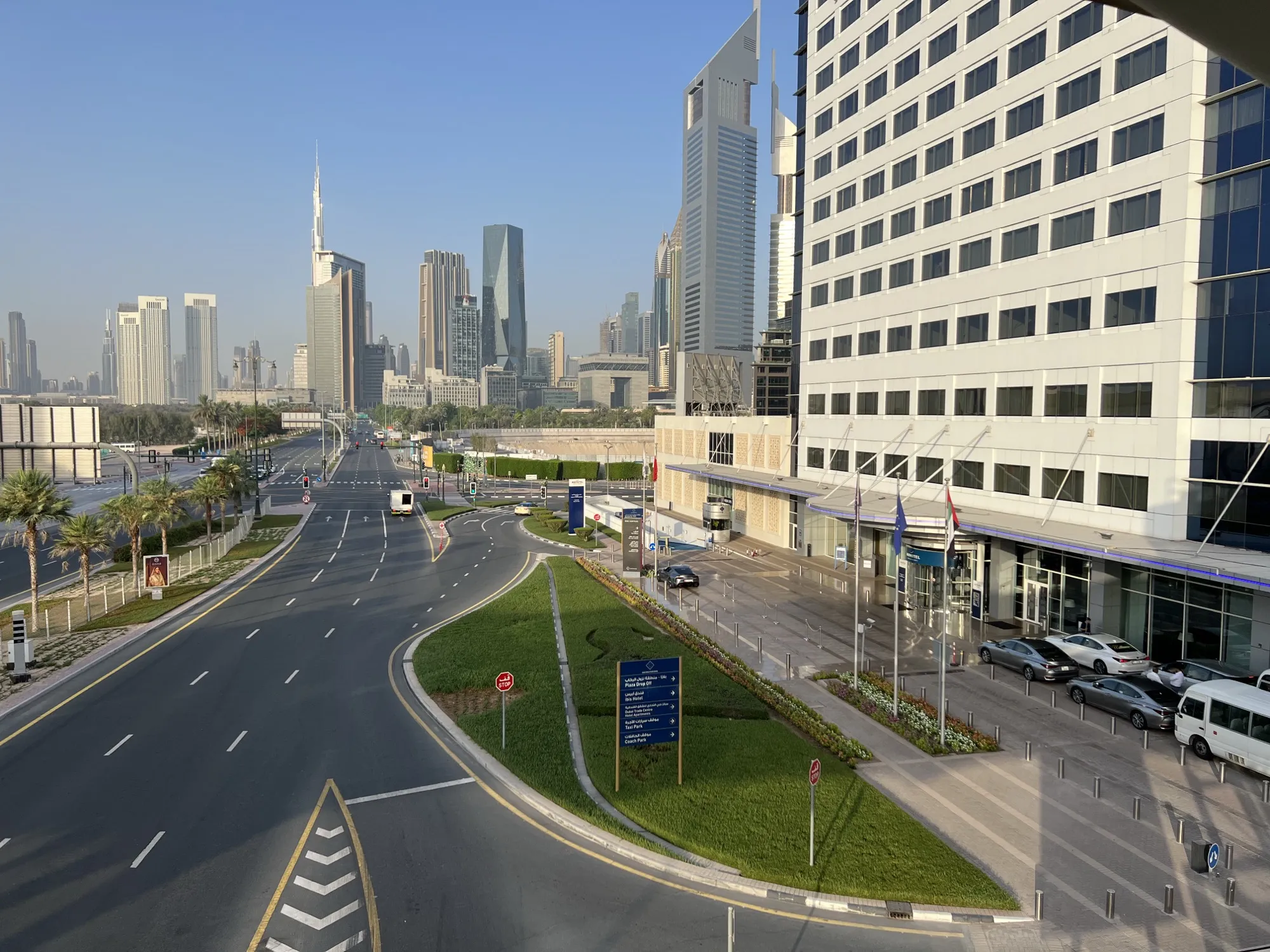 Sheikh Zayed Road curving past the Dubai World Trade Centre hotel entrance, with the Downtown skyline beyond