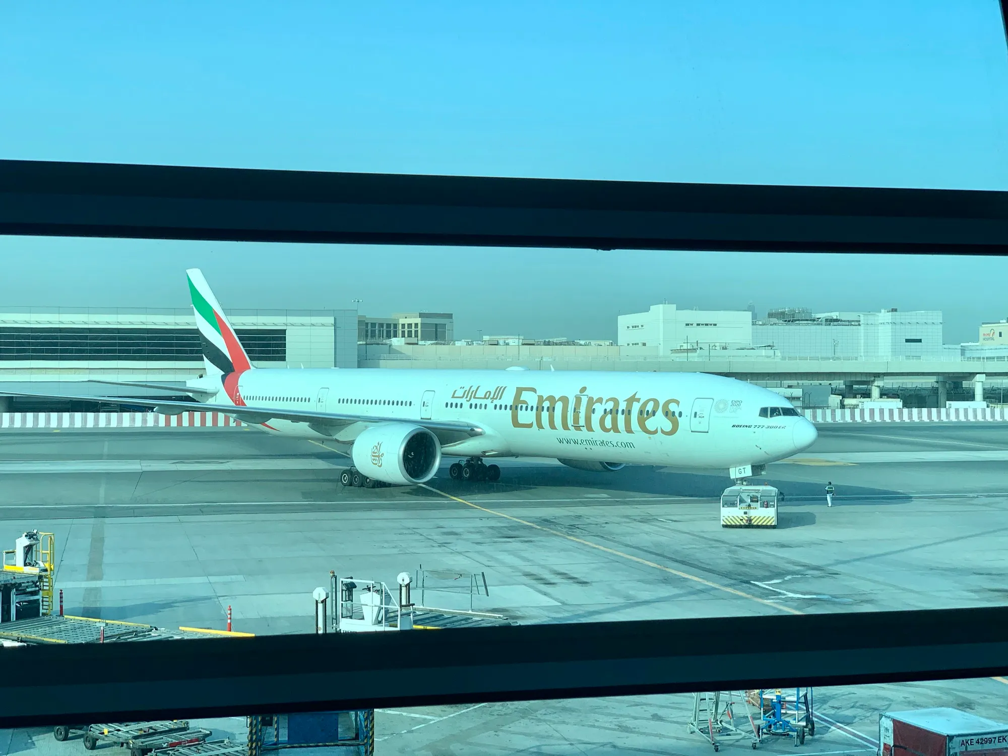 An Emirates Boeing 777 on the apron, seen through the window of Terminal 3 at Dubai International Airport