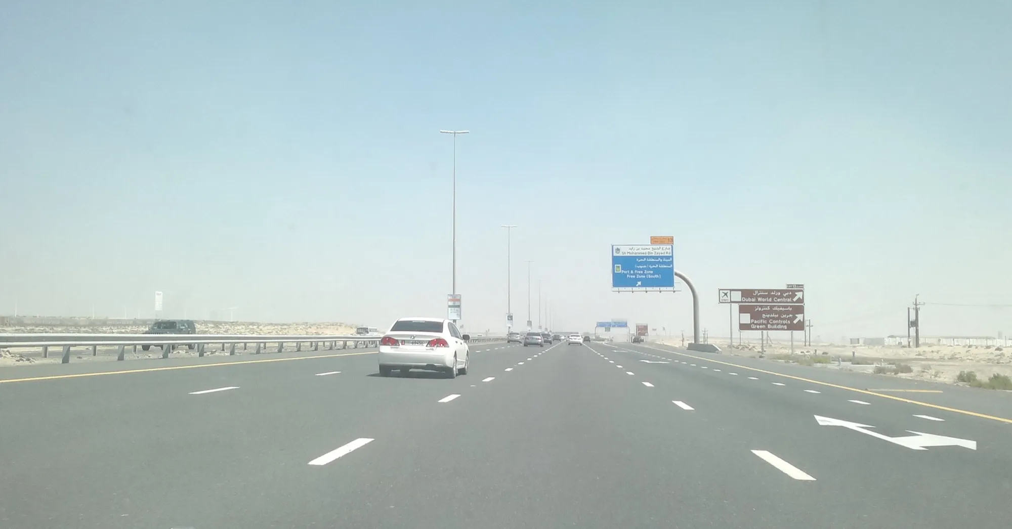 A multi-lane desert highway between Abu Dhabi and Dubai, with overhead direction signs