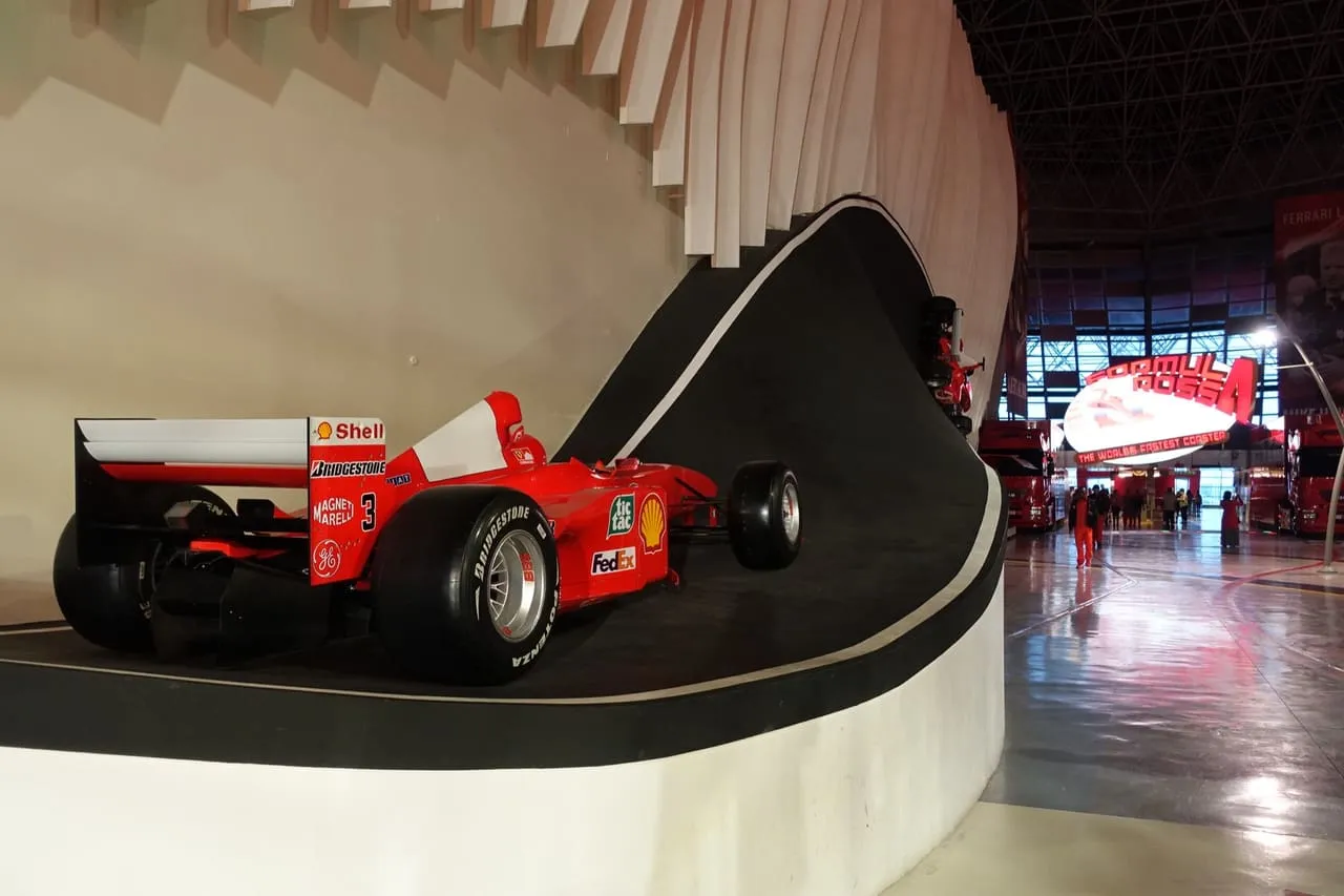 A Formula 1 car on a curved display ramp inside Ferrari World Abu Dhabi, with the Formula Rossa sign behind