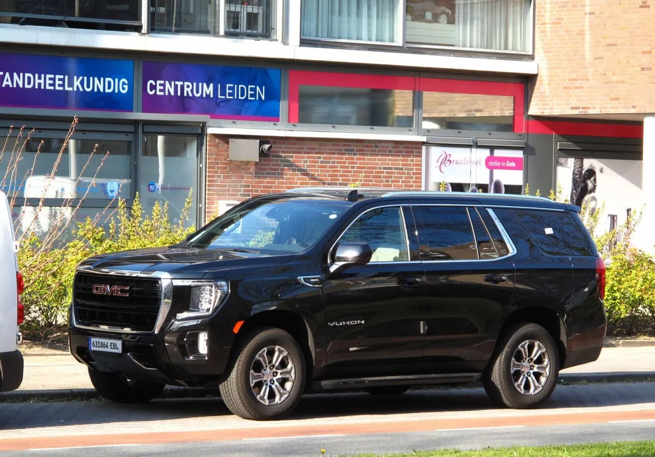 A black GMC Yukon full-size SUV parked at the kerb, seen from the front left