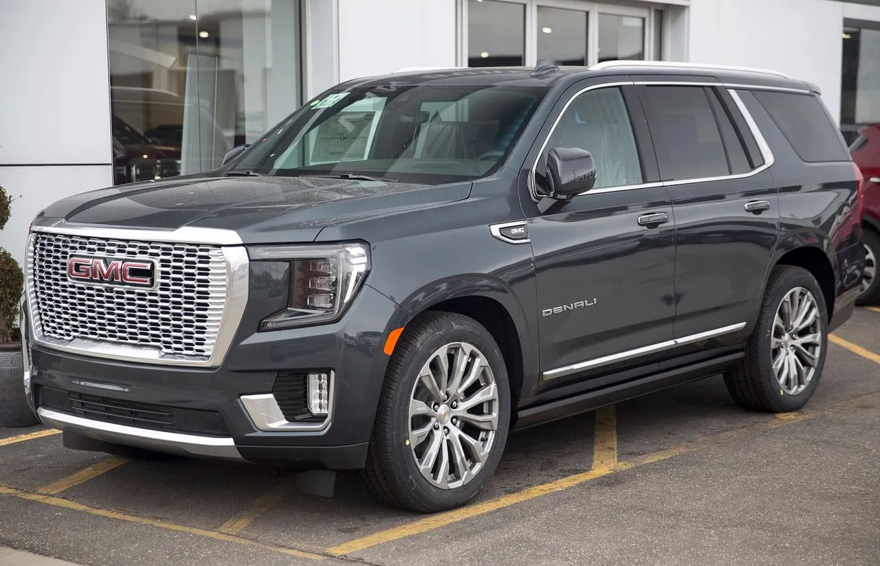 A dark grey GMC Yukon Denali, a three-row SUV, parked outside a dealership