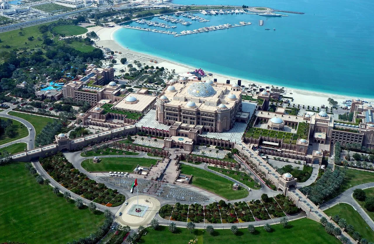 Emirates Palace in Abu Dhabi seen from the air, with its domes, front gardens, beach and marina