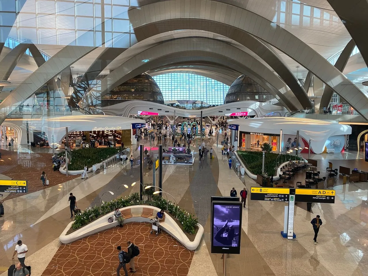 Passengers walking through the main hall of Terminal A at Zayed International Airport, Abu Dhabi, under its curved white roof