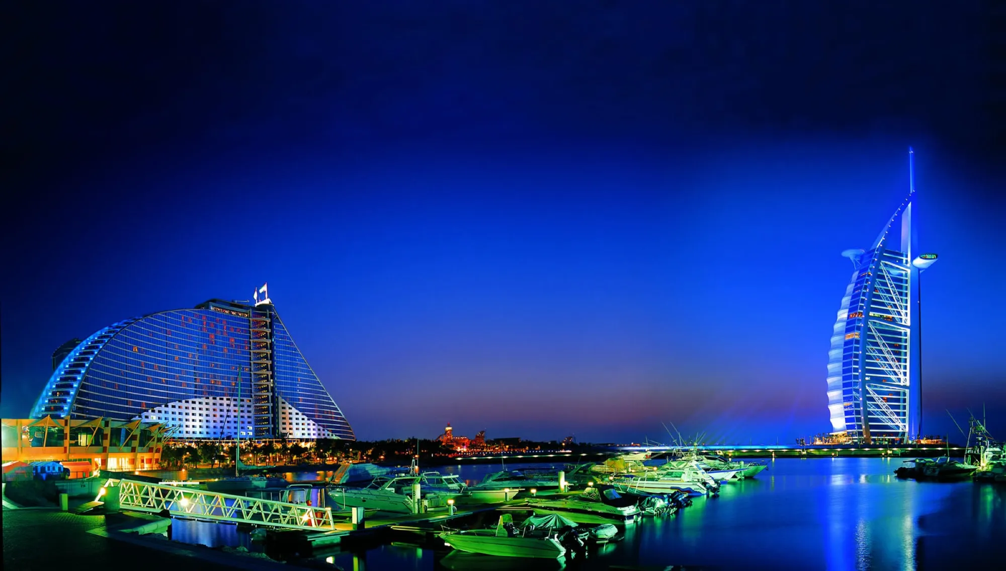Jumeirah Beach Hotel and the Burj Al Arab lit up at night over the marina in Dubai
