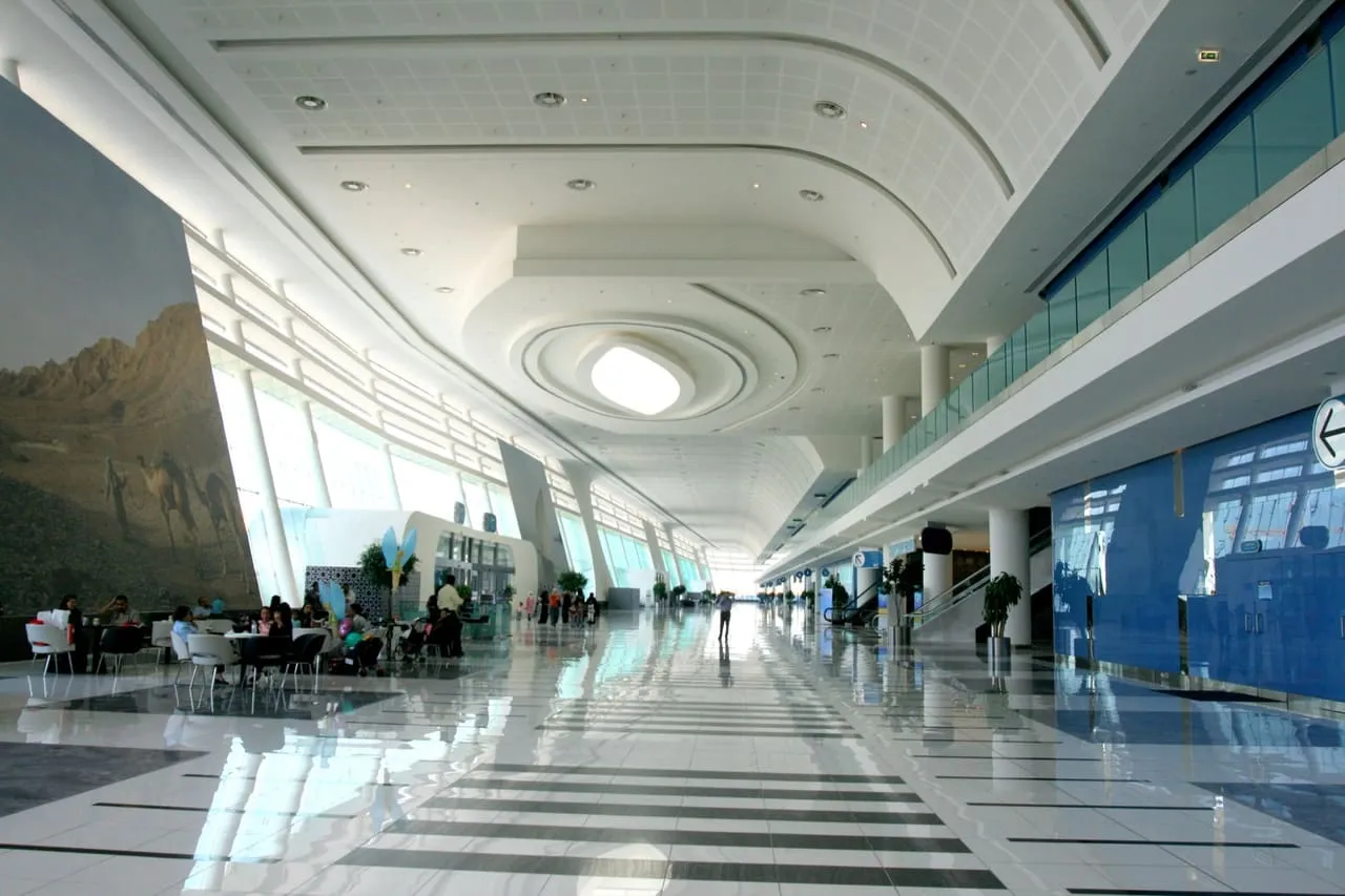 The long white concourse inside ADNEC Centre Abu Dhabi, with a cafe on the left