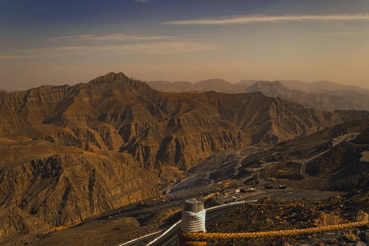 The Hajar Mountains on Jebel Jais at sunset, with Jais Road winding along the slope below