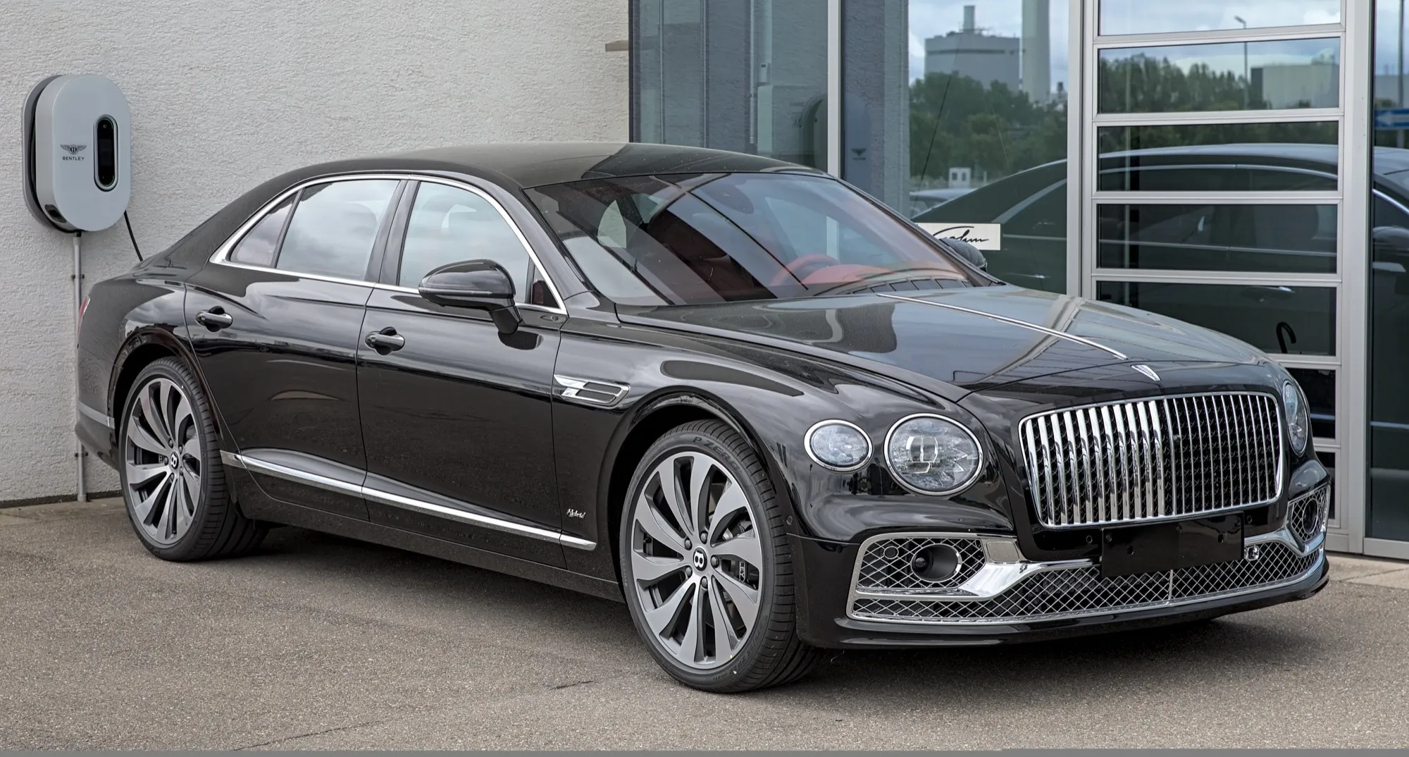 A black Bentley Flying Spur Hybrid parked beside a charging point