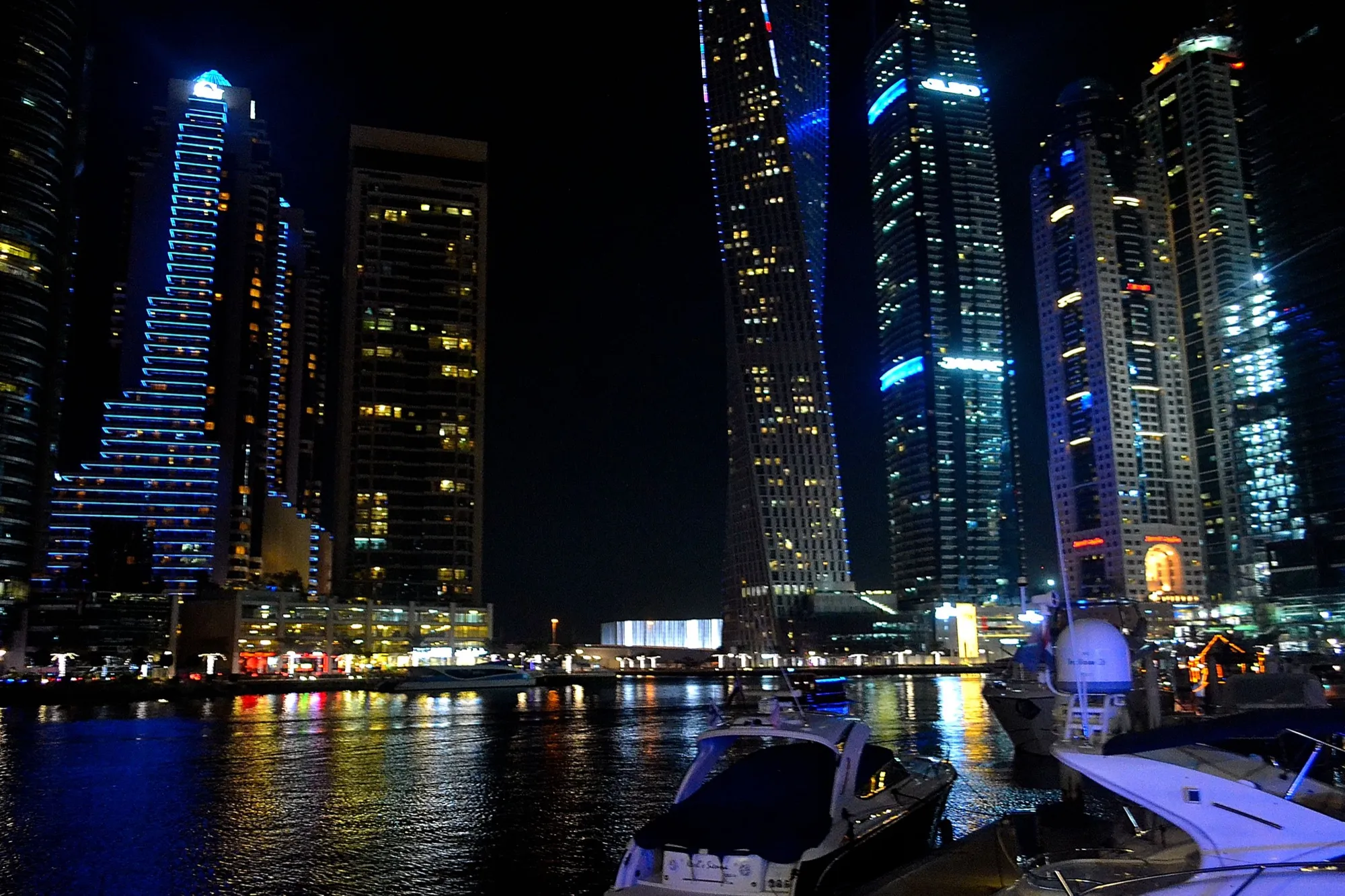 Dubai Marina towers and moored boats lit up at night
