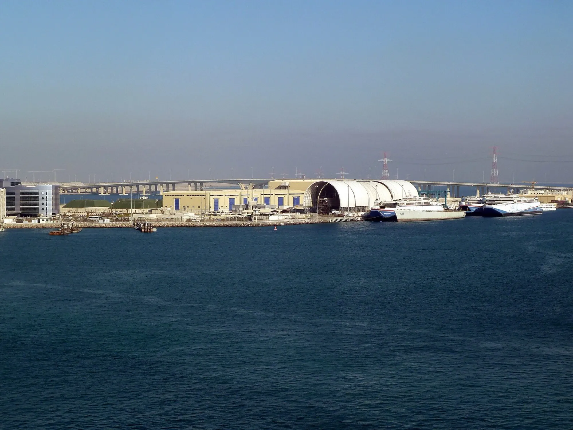 The waterfront at Zayed Port in Abu Dhabi, with the Saadiyat Bridge behind the quayside sheds and ferries