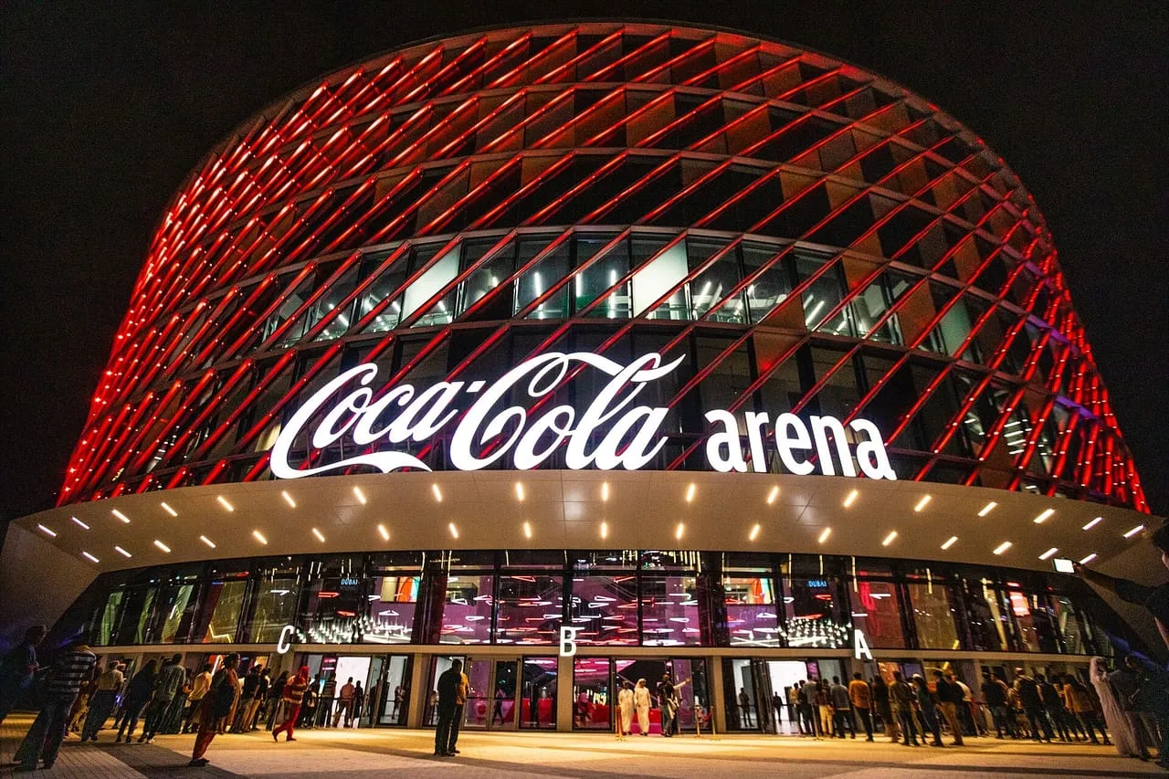 Coca-Cola Arena in Dubai lit up at night, with concert-goers outside entrances A, B and C