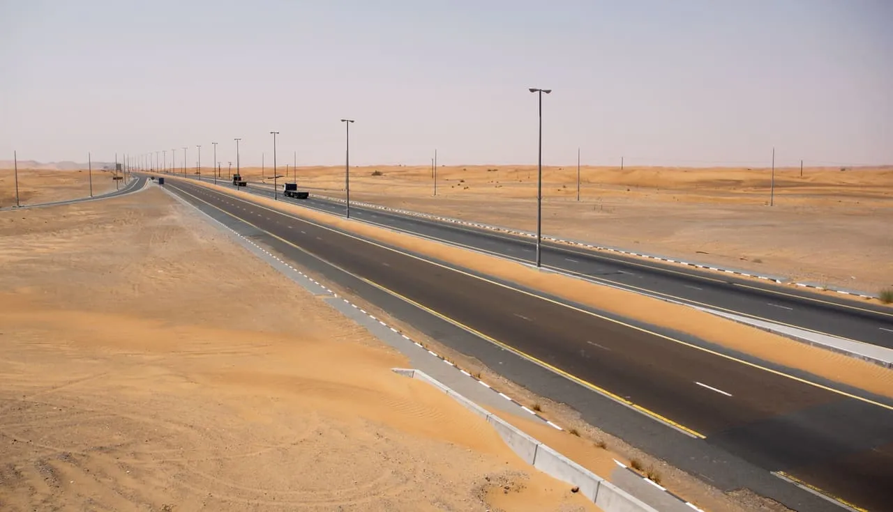 A lit dual carriageway crossing open desert in Sharjah emirate