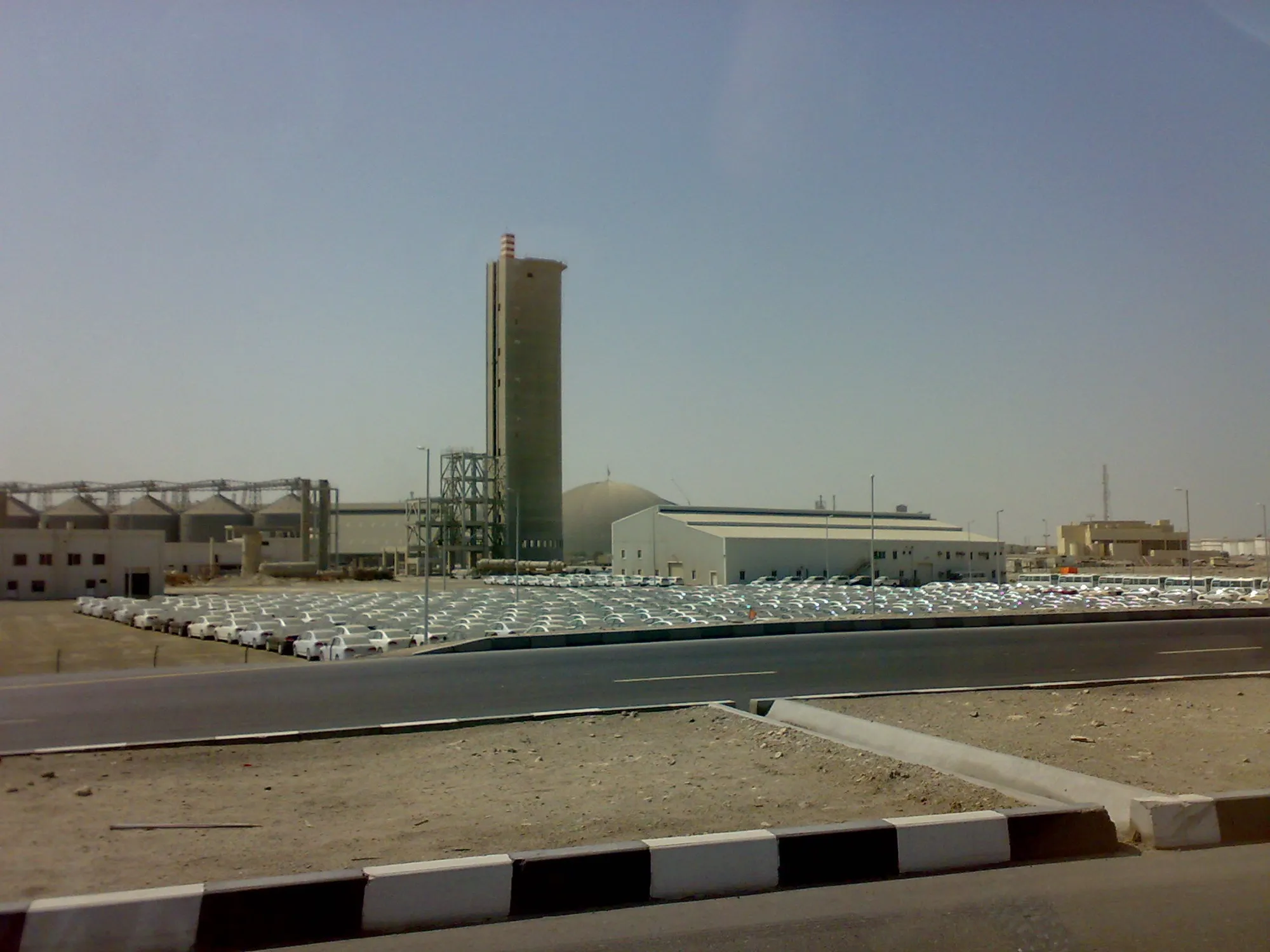 Warehouses, silos and a vehicle storage yard beside a road in the Jebel Ali Free Zone, Dubai