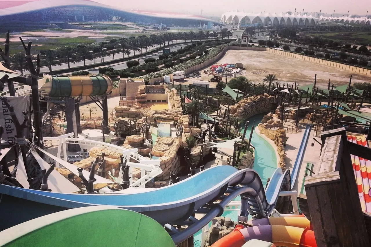 Water slides at Yas Waterworld, with the red-roofed Ferrari World building and the Yas Marina Circuit grandstands behind