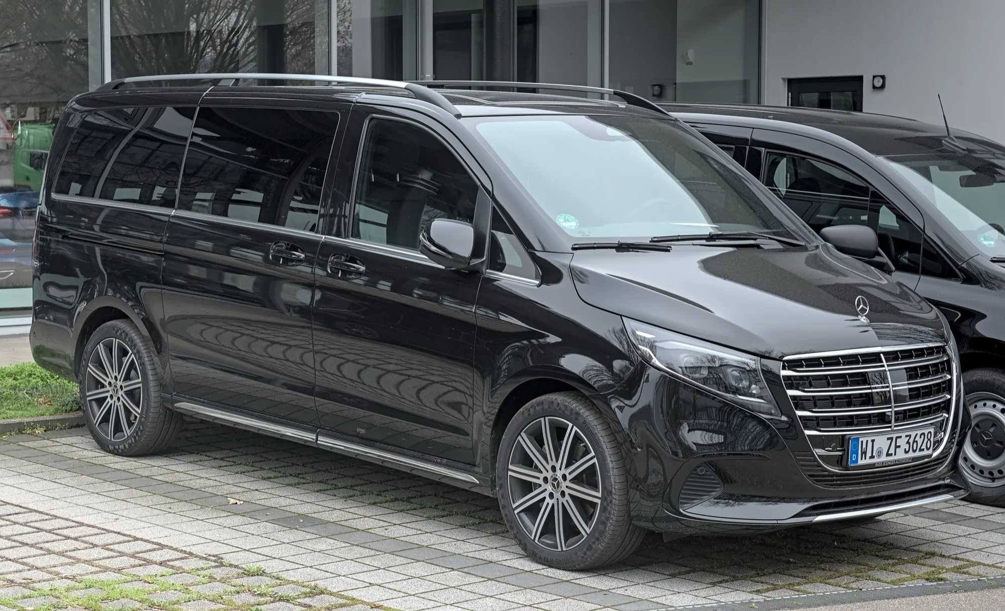 A black Mercedes-Benz V-Class, a six-seat luxury van, parked beside another V-Class