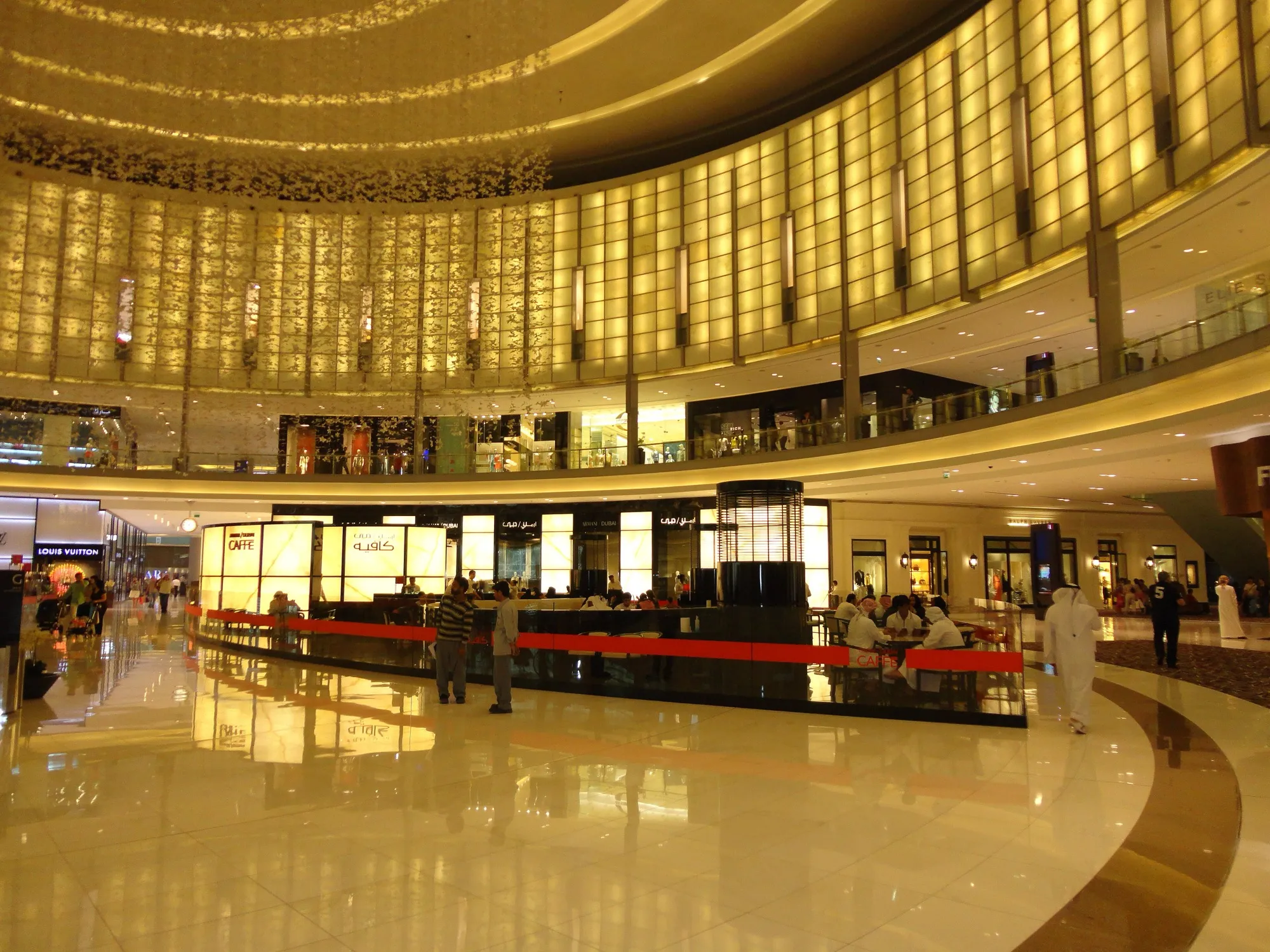 The curved atrium of the Fashion Avenue wing inside Dubai Mall, with a cafe and shopfronts on the polished floor