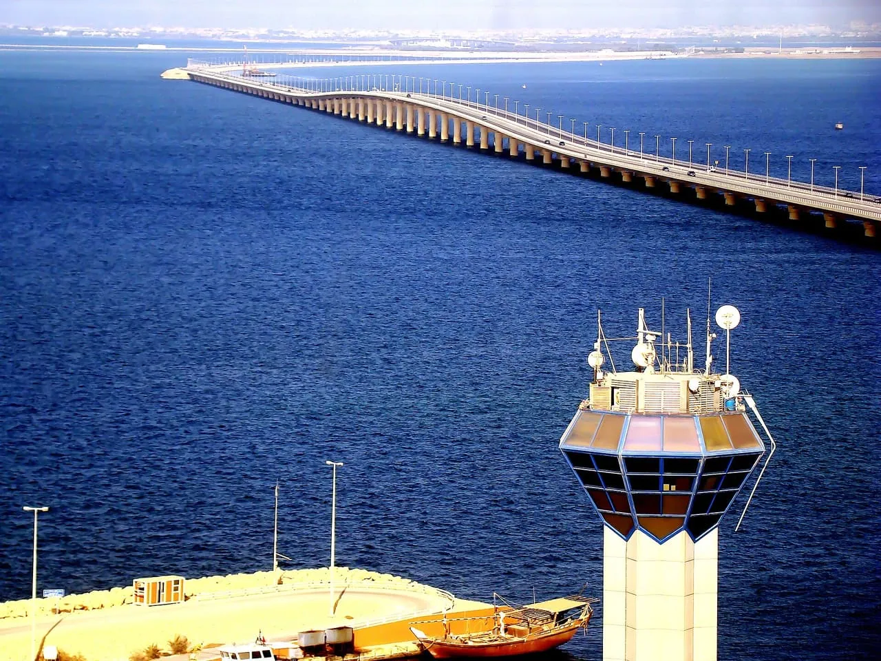 The King Fahd Causeway between Saudi Arabia and Bahrain seen from above, with a radar tower and a moored dhow in the foreground
