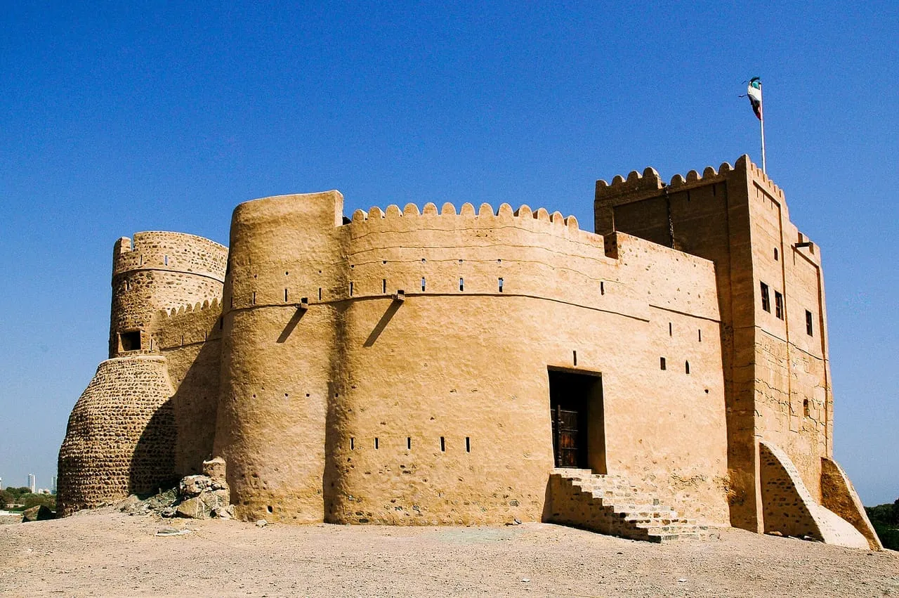 Fujairah Fort, a restored mud-brick fort with round towers and a square keep, under a clear blue sky