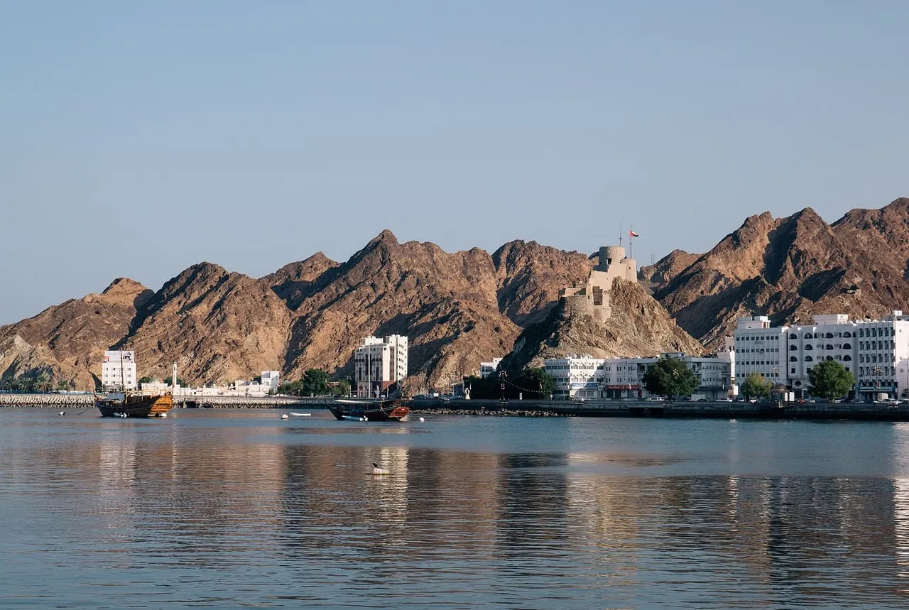 Muttrah Fort on its rocky hill above the corniche and harbour in Muscat, with dhows moored in the bay