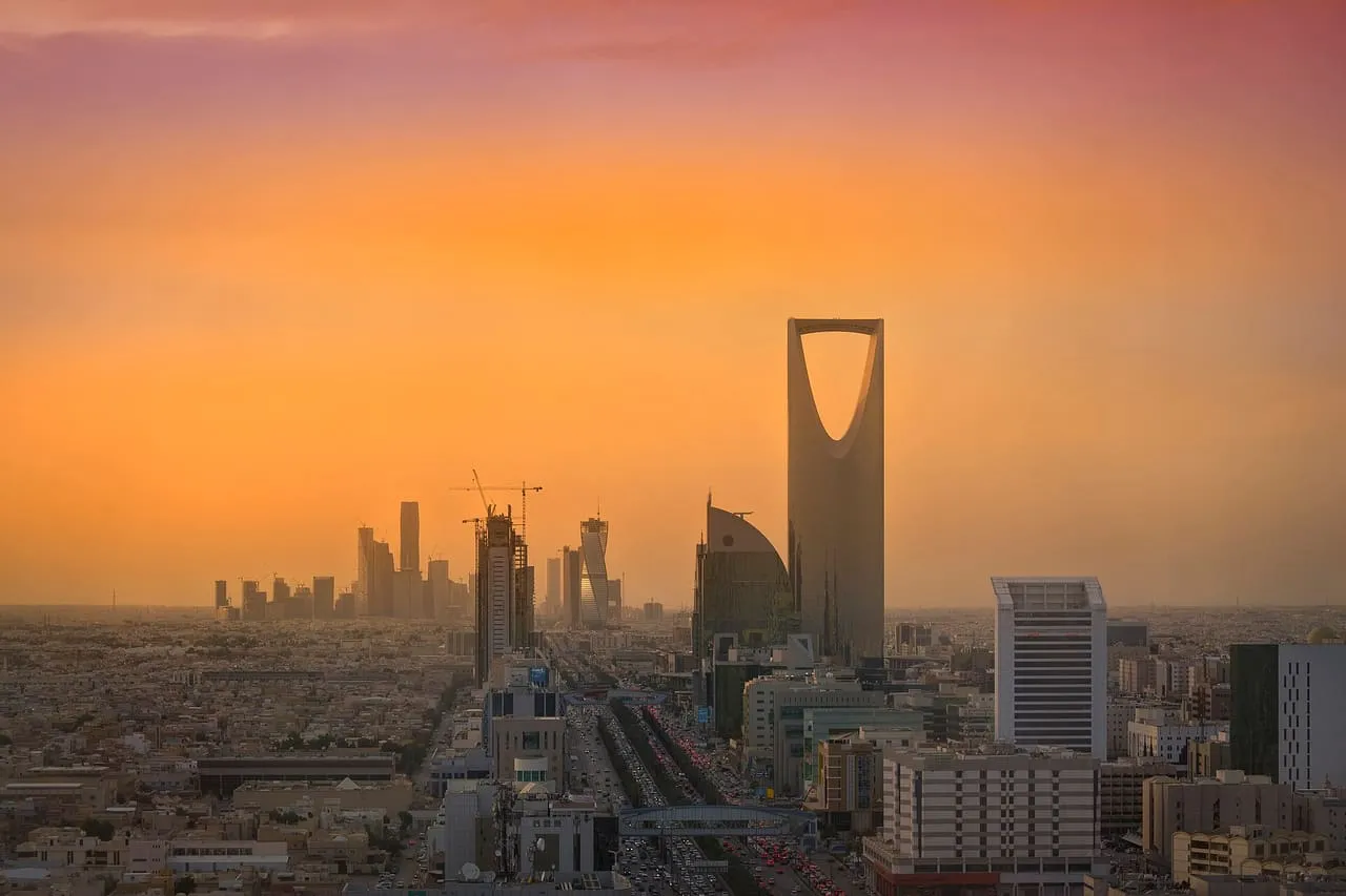 The Riyadh skyline at sunset, with Kingdom Centre in front, the towers of the King Abdullah Financial District behind and traffic on King Fahd Road