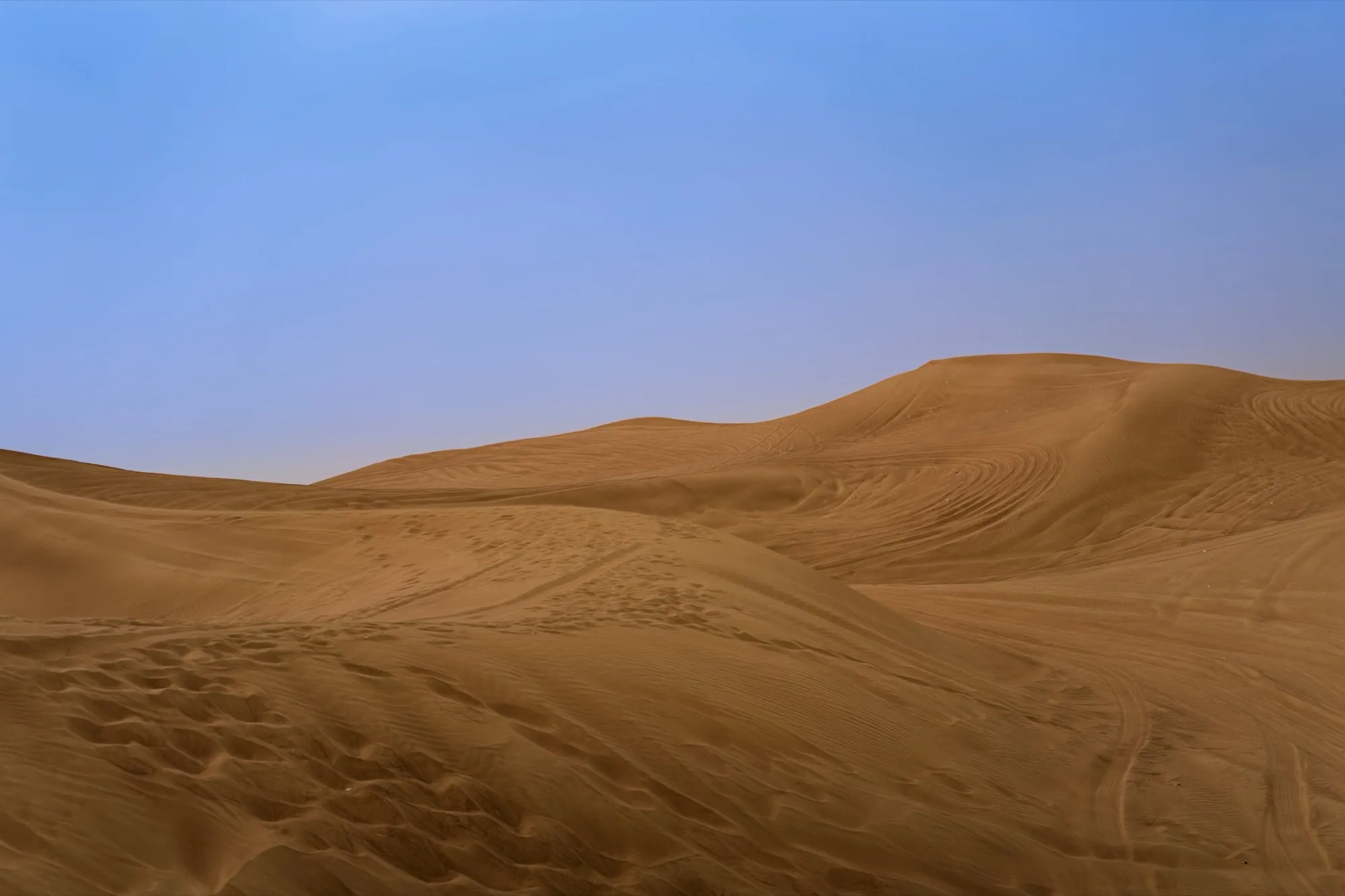 Rolling red sand dunes in the desert outside Dubai under a clear sky