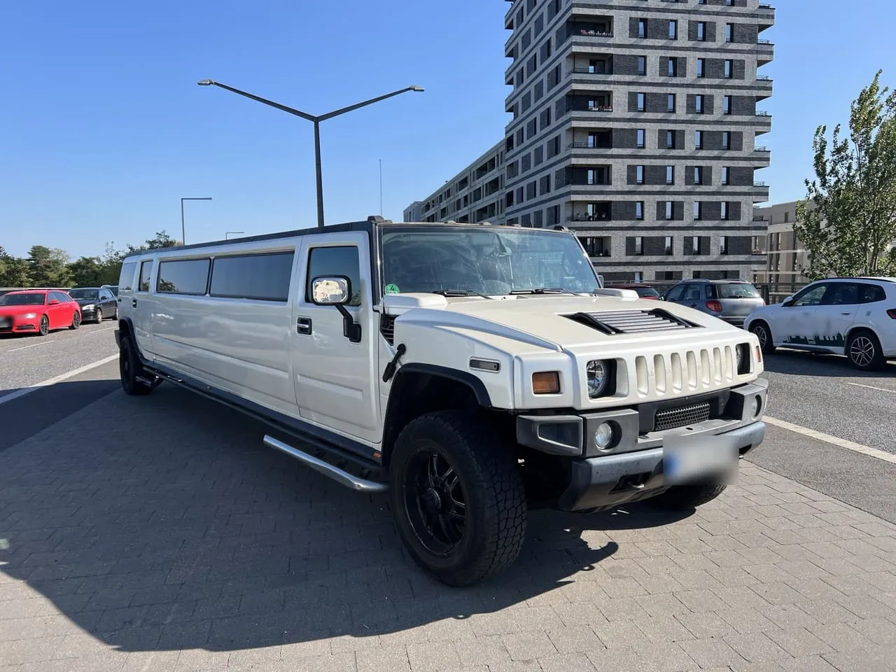 White Hummer H2 stretch limousine seen from the front three-quarter, a representative image, not the partner's car