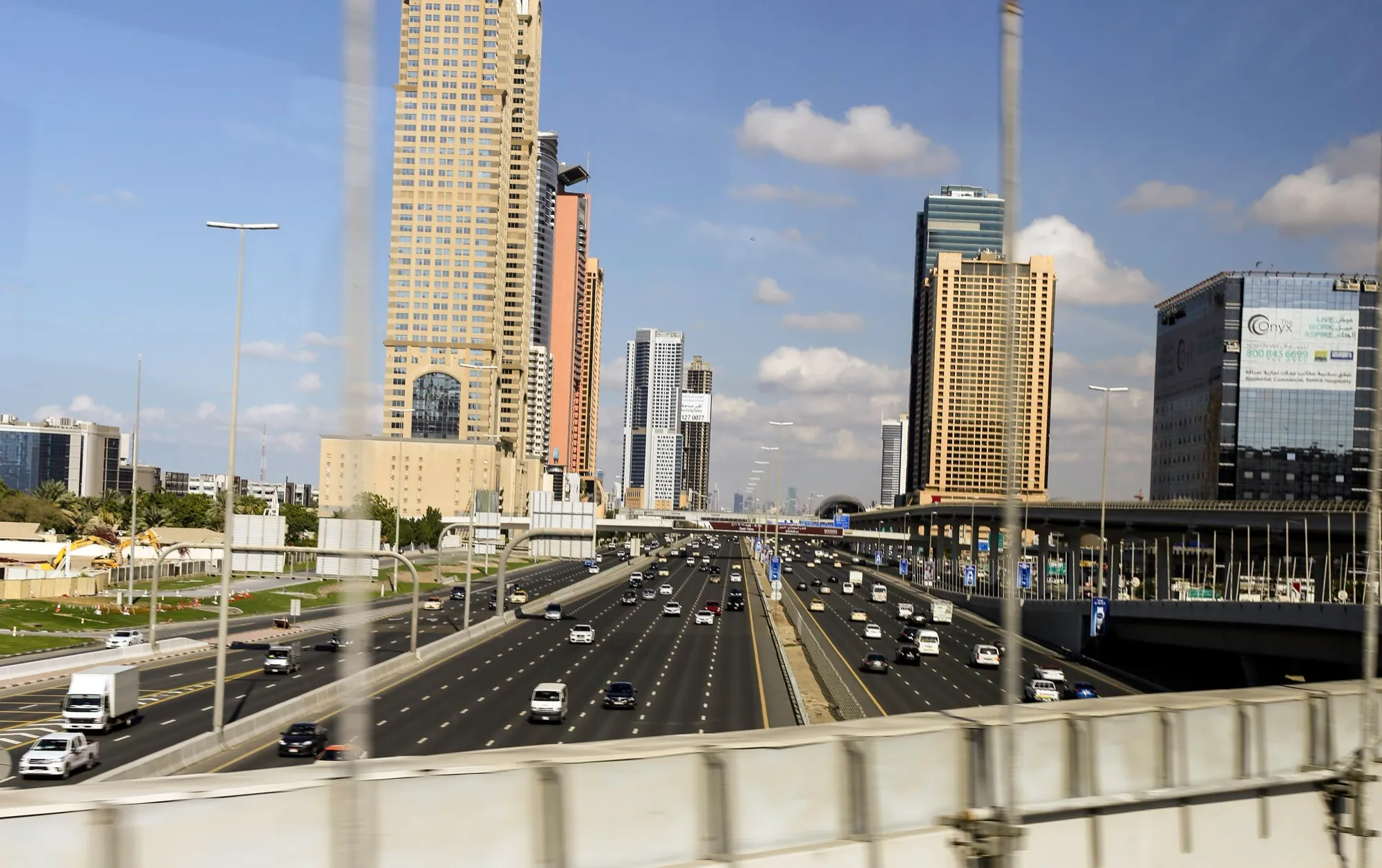 Eight lanes of Sheikh Zayed Road seen from a bridge, with Dubai towers on both sides