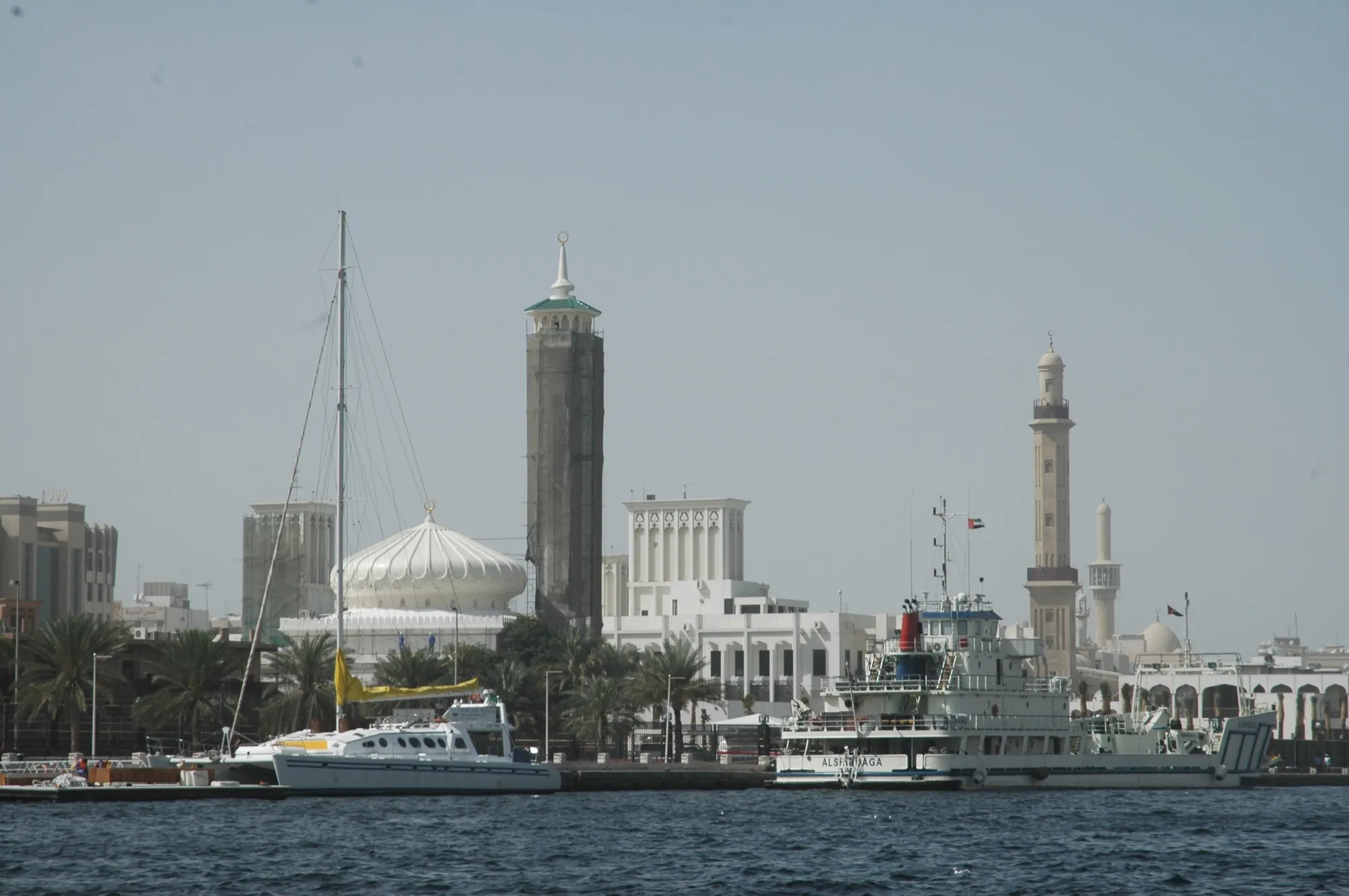 Boats on Dubai Creek with mosque minarets and old Dubai buildings behind