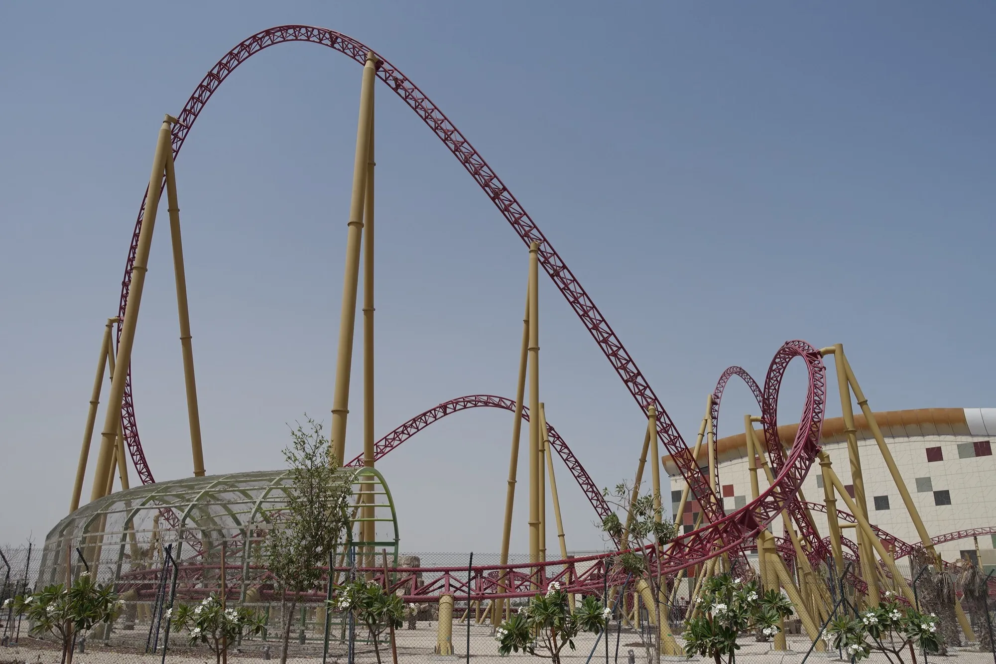 A red steel roller coaster loop under the dark domed ceiling at IMG Worlds of Adventure