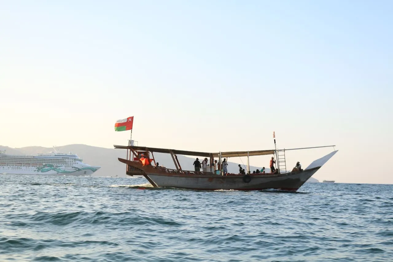 A wooden dhow flying the Omani flag on a day cruise off Khasab
