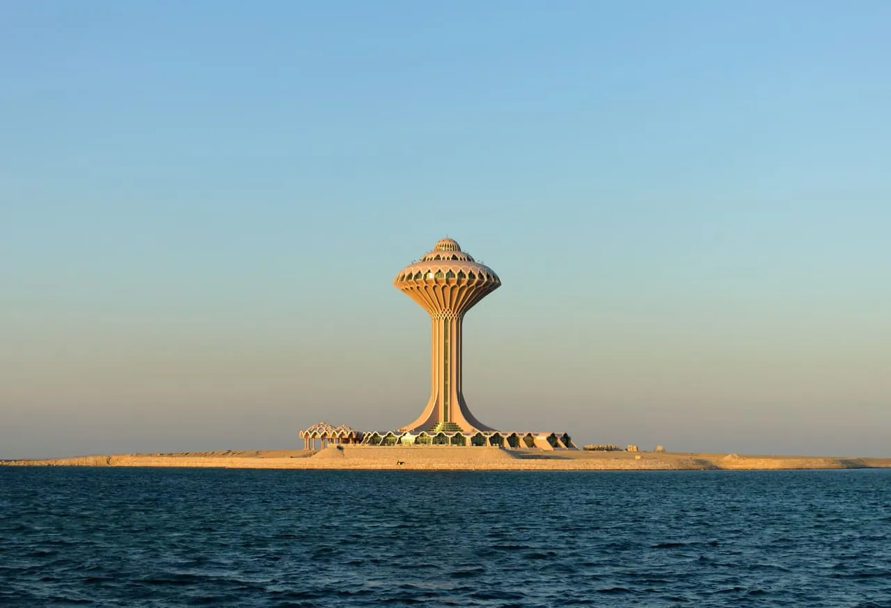 The Al Khobar Water Tower standing on its own spit of land in the Gulf, seen from the water