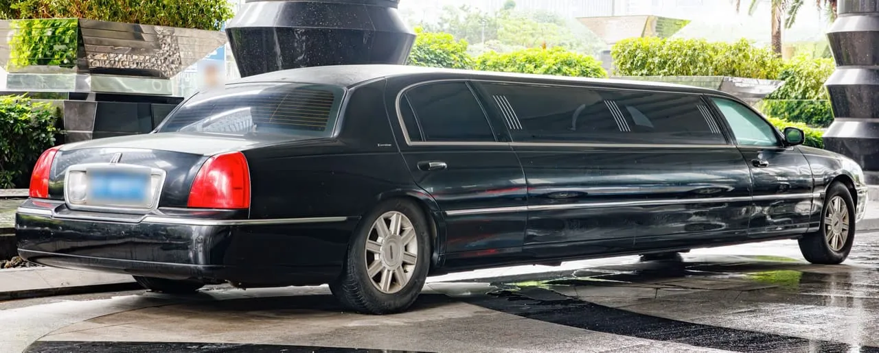 Black Lincoln Town Car stretch limousine at a hotel entrance, a representative image, not the partner's car