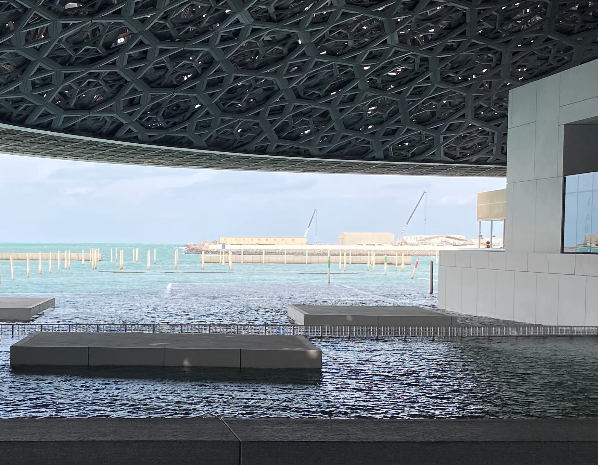 The dome edge, floating stone platforms and the sea beyond at Louvre Abu Dhabi