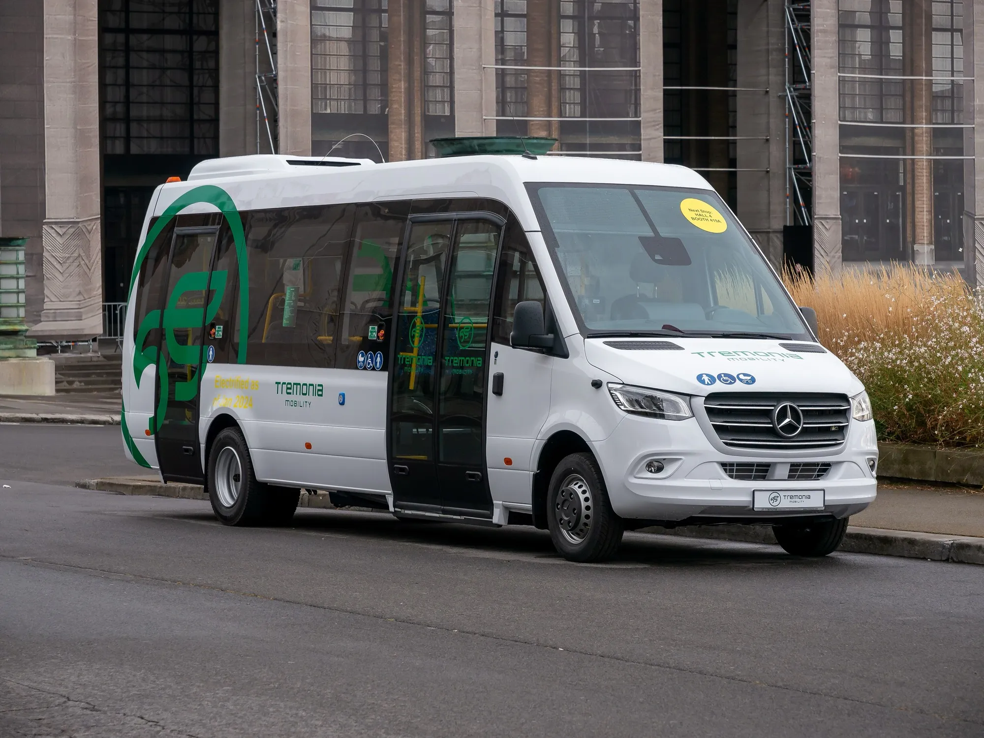 A white Mercedes-Benz Sprinter-based minibus with a wide side door, the van type used for 13 and 19 seat guest shuttles