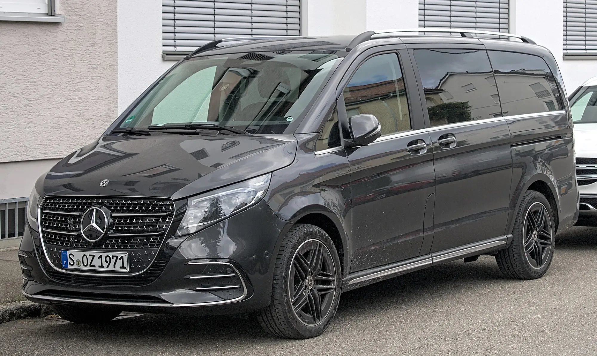 A dark grey Mercedes-Benz V-Class with a sliding side door, parked on a street