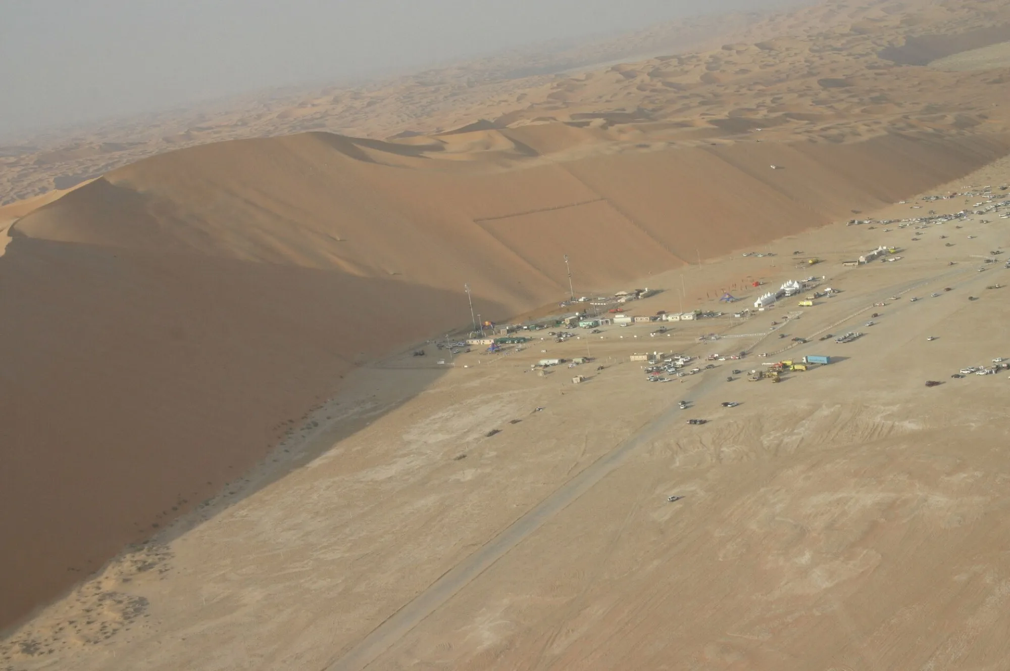 Aerial view of the Tal Moreeb dune with event tents and parked vehicles at its foot