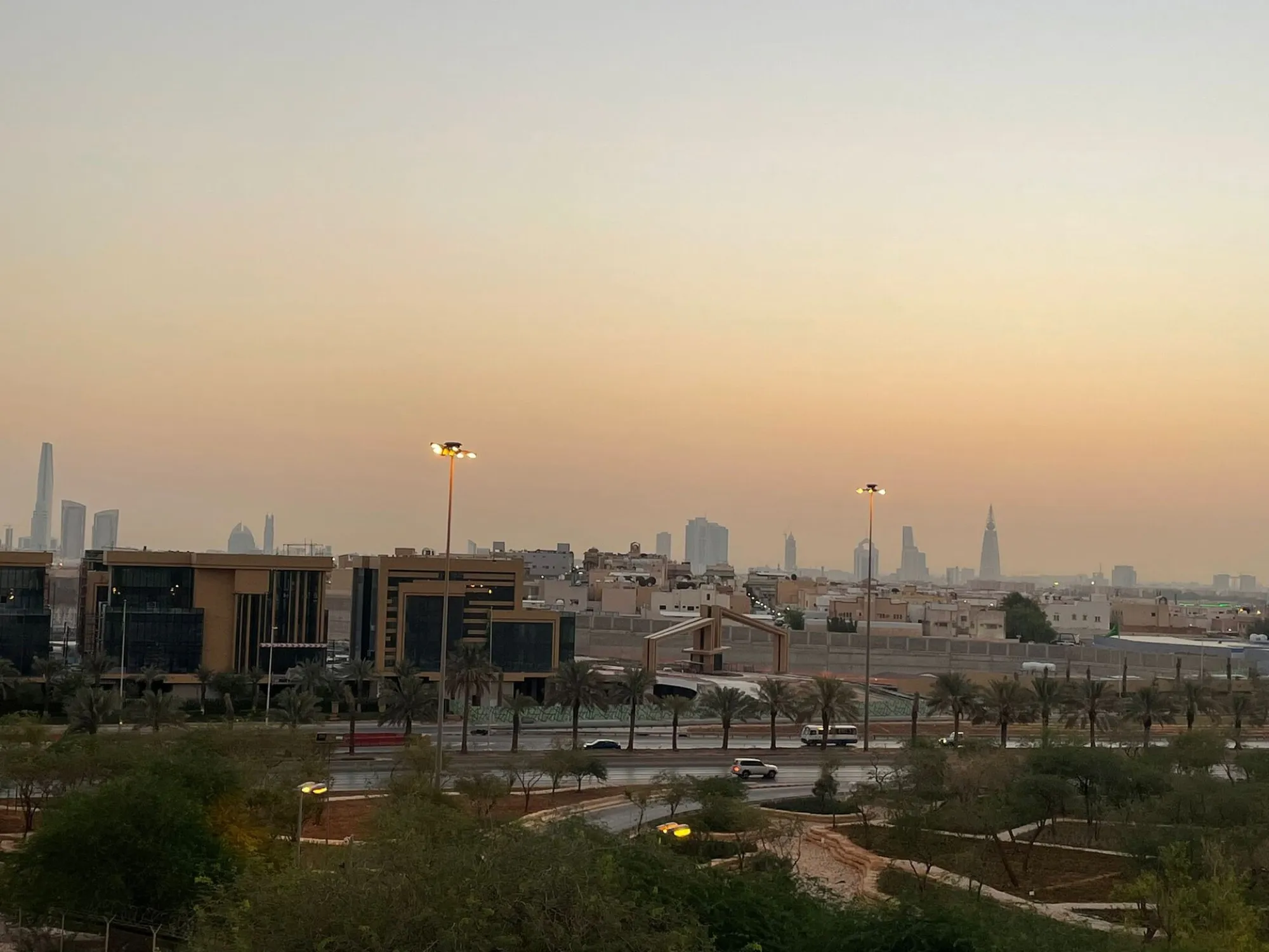 The Riyadh skyline at dusk, with the Kingdom Centre and Al Faisaliyah towers behind a landscaped highway