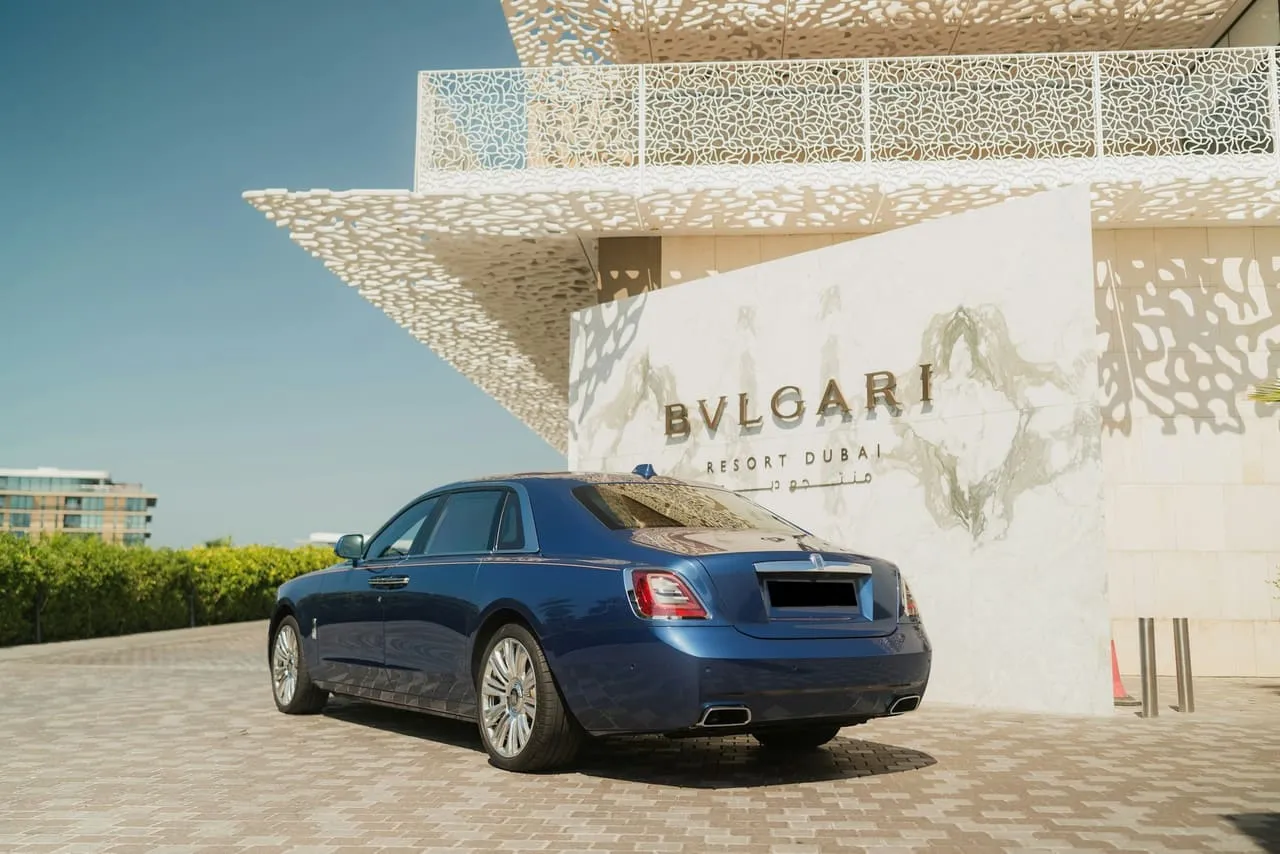 A blue Rolls-Royce Ghost parked at the entrance of the Bulgari Resort Dubai on a clear day