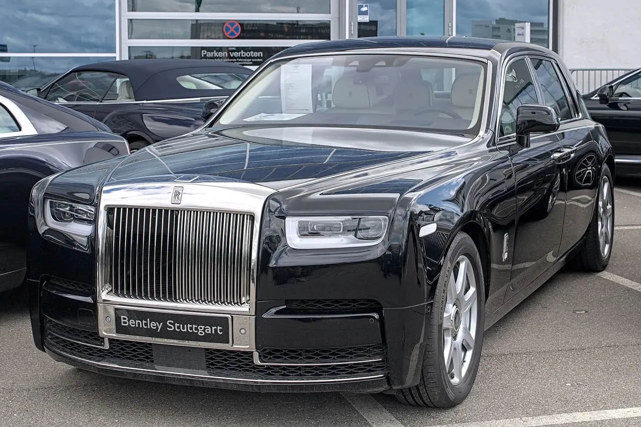 A black Rolls-Royce Phantom, the current eighth generation, parked outside a dealership