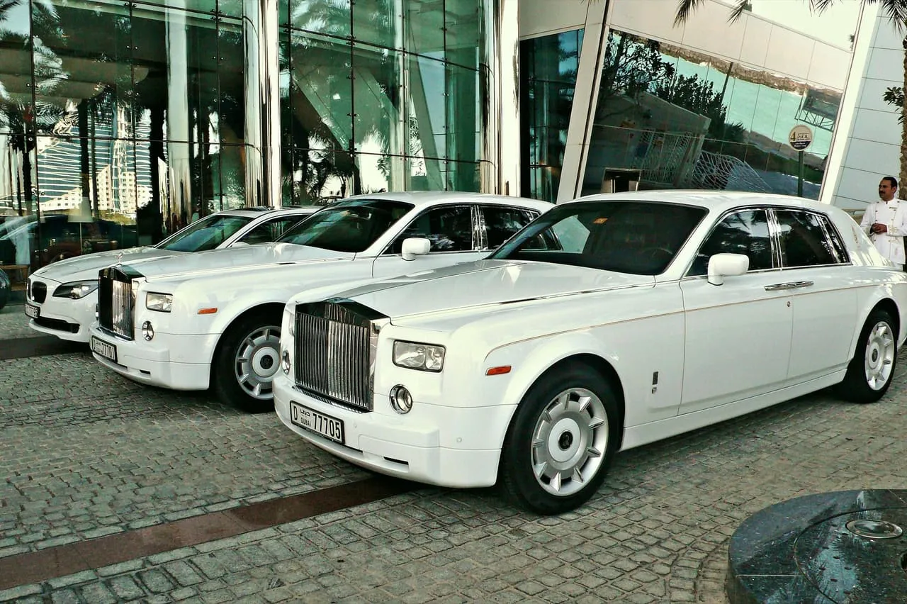 Two white Rolls-Royce Phantoms parked at a hotel entrance in Dubai