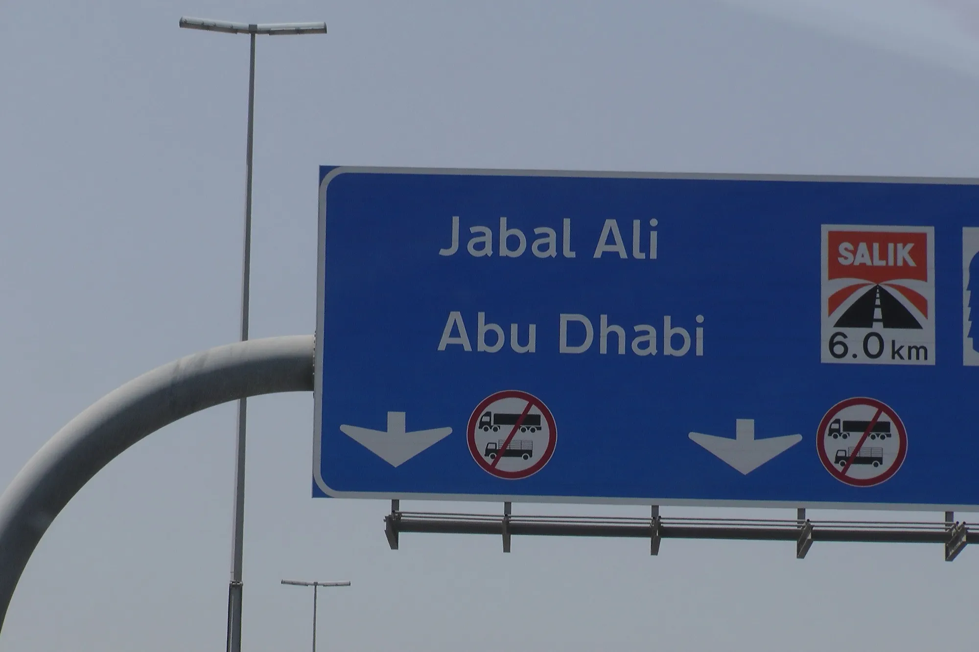 Overhead road sign in Dubai for Jebel Ali and Abu Dhabi, marking a Salik toll gate 6 km ahead